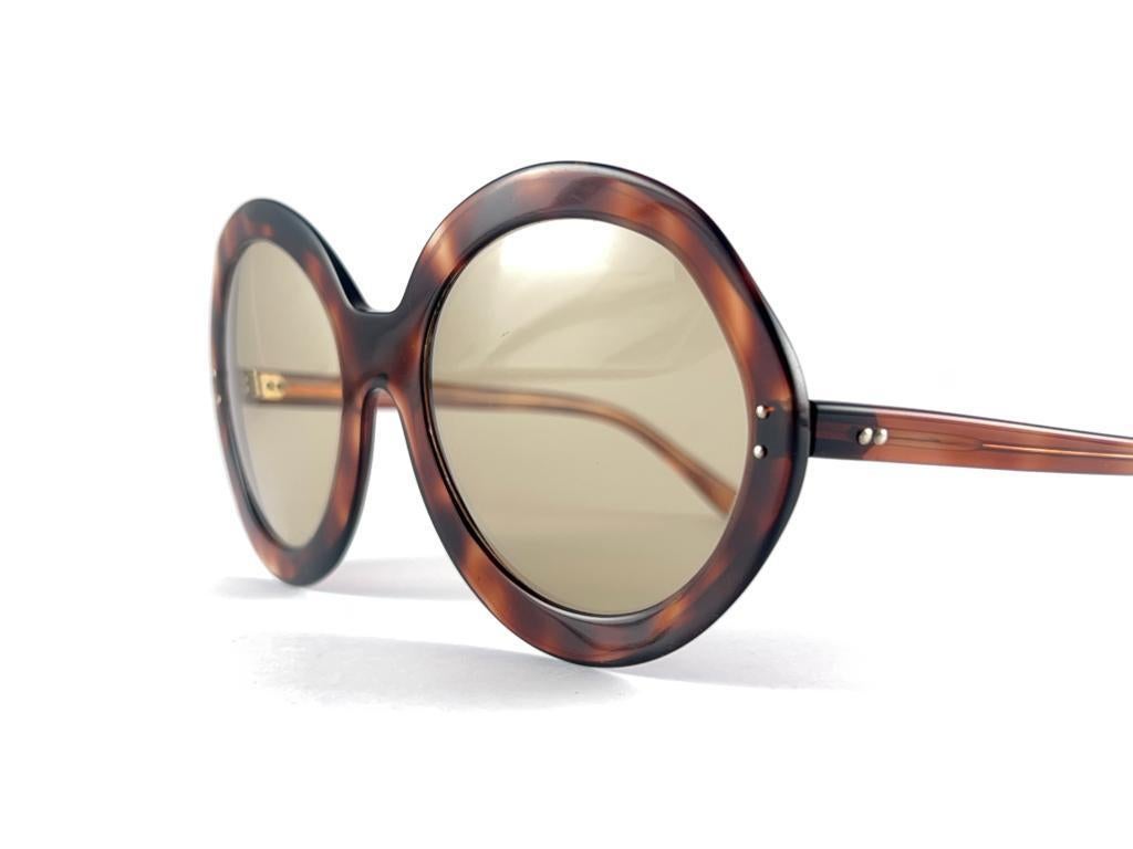 New Vintage Round Oversized Tortoise Frame Holding  A Pair Of Spotless Light Brown Lenses
Superb Quality,  Even Better Design.
New, Never Worn Or Displayed
This Item May Show Minor Sign Of Wear Due To More Than 50 Years Of Storage



Made In