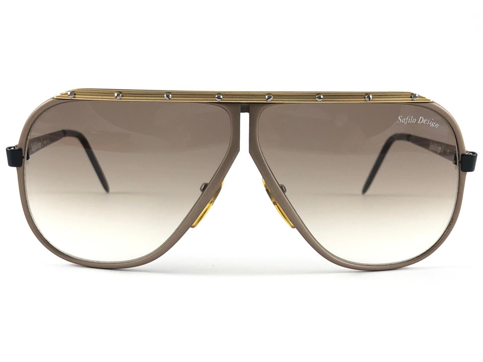 New Vintage Safilo, a balanced combination of Italian craftsmanship, design, functionality and striking aesthetics, this model showcases a Copper mate with Gold accents Aviator Frame holding Brown gradient lenses.

New, never worn or displayed.
Made