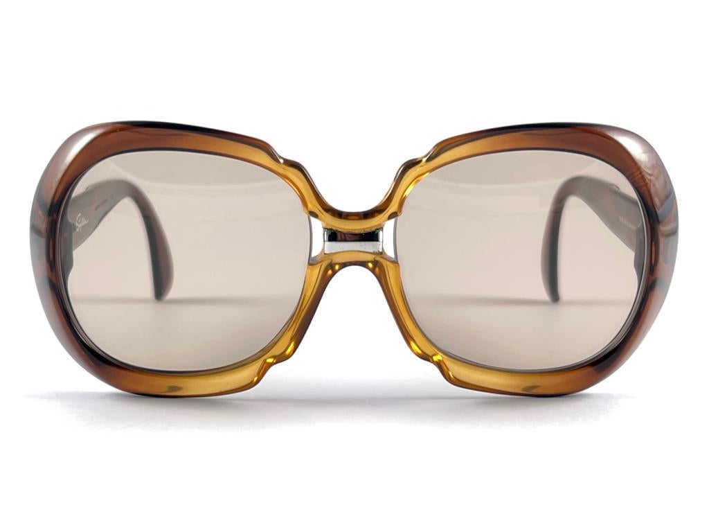 

New Vintage Saphira Transluzent Bernstein & Honig mit silbernen Akzenten  Sonnenbrillenrahmen mit einem makellosen Paar originaler mittelbrauner Gläser.   

Dieser Artikel kann einige kleinere Anzeichen von Verschleiß aufgrund von Lagerung und