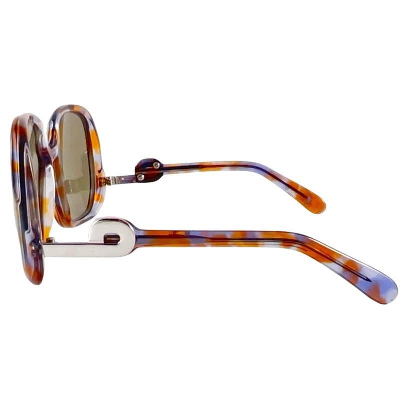 New Vintage Collector Item Silhouette Clear Colours and Silver accents  Monture de lunettes de soleil avec une paire de verres gris moyen impeccables.   

Fabriqué en Allemagne dans les années 1970.

AVANT : 15 CMS


HAUTEUR DE LA LENTILLE : 5