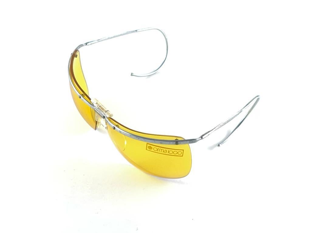 
New Ultra Rare Collectors Pair Of Vintage Sol Amor Wrap Semi Rimless 1960'S Sunglasses
Lightweight Silver Metal Frame Sporting Curled Ear Temples Holding Original Yellow Lenses

This Pair May Show Minor Sign Of Wear Due To More Than 60 Years Of