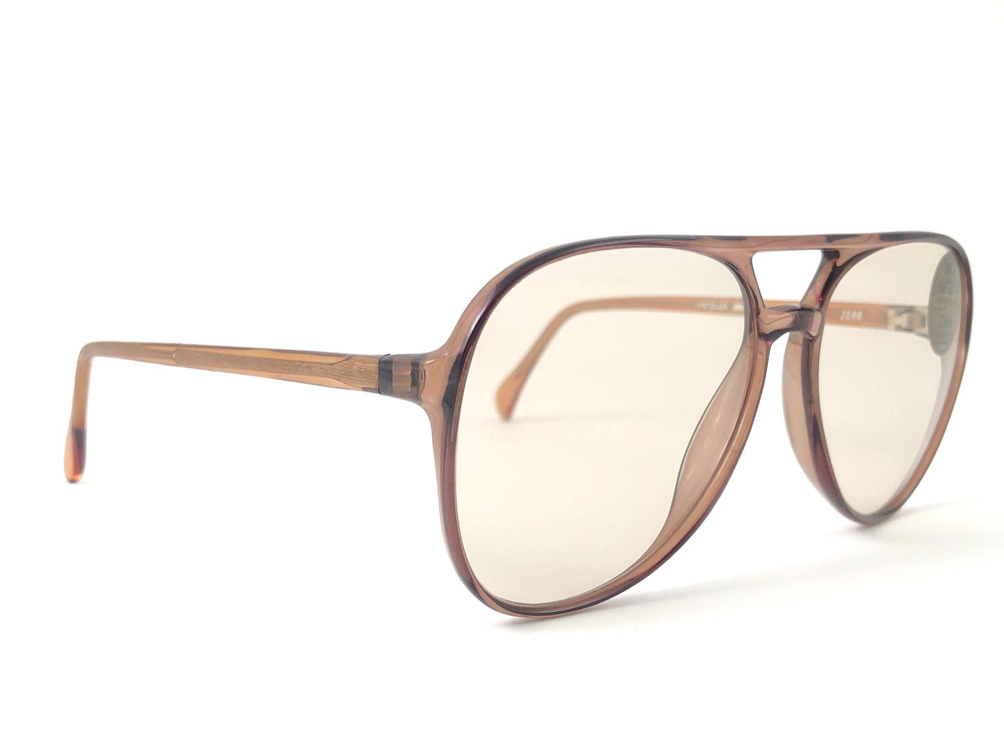 Lunettes de soleil monture aviateur Zeiss Umbramatic. Fabriqué en Allemagne de l'Ouest dans les années 1980. 

Monture translucide surdimensionnée contenant une paire de lentilles marron clair impeccables. Cadre présentant une légère usure due au