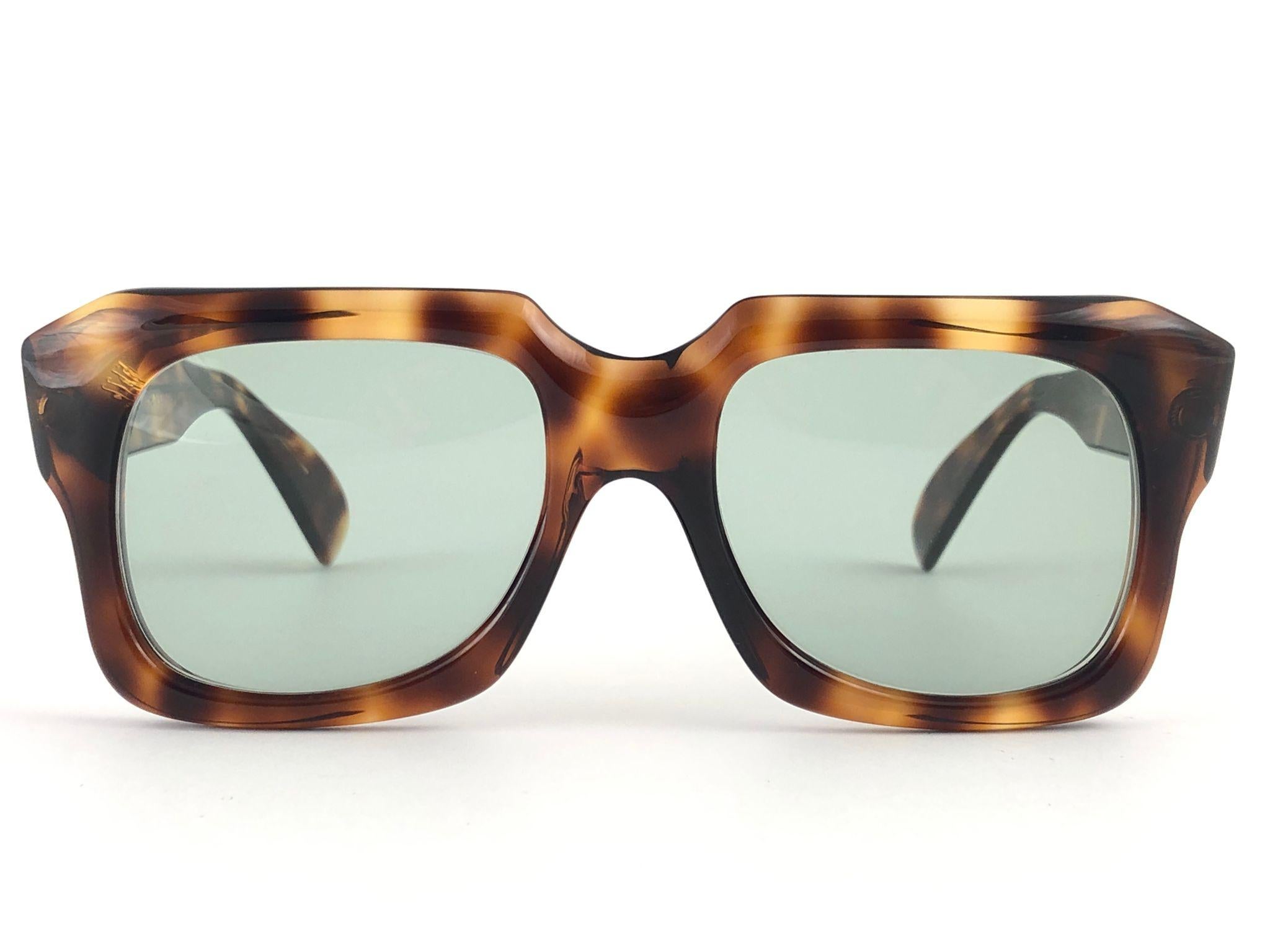New vintage Zollitsch 301 tortoise robust oversized frame. Spotless medium green lenses.
This pair have slight wear on them due to to nearly 40 years of storage.  

FRONT : 15 CM
LENS  HEIGHT : 4.3 CMS
LENS WIDTH : 5.4 CMS
TEMPLES : 14 CMS
`
