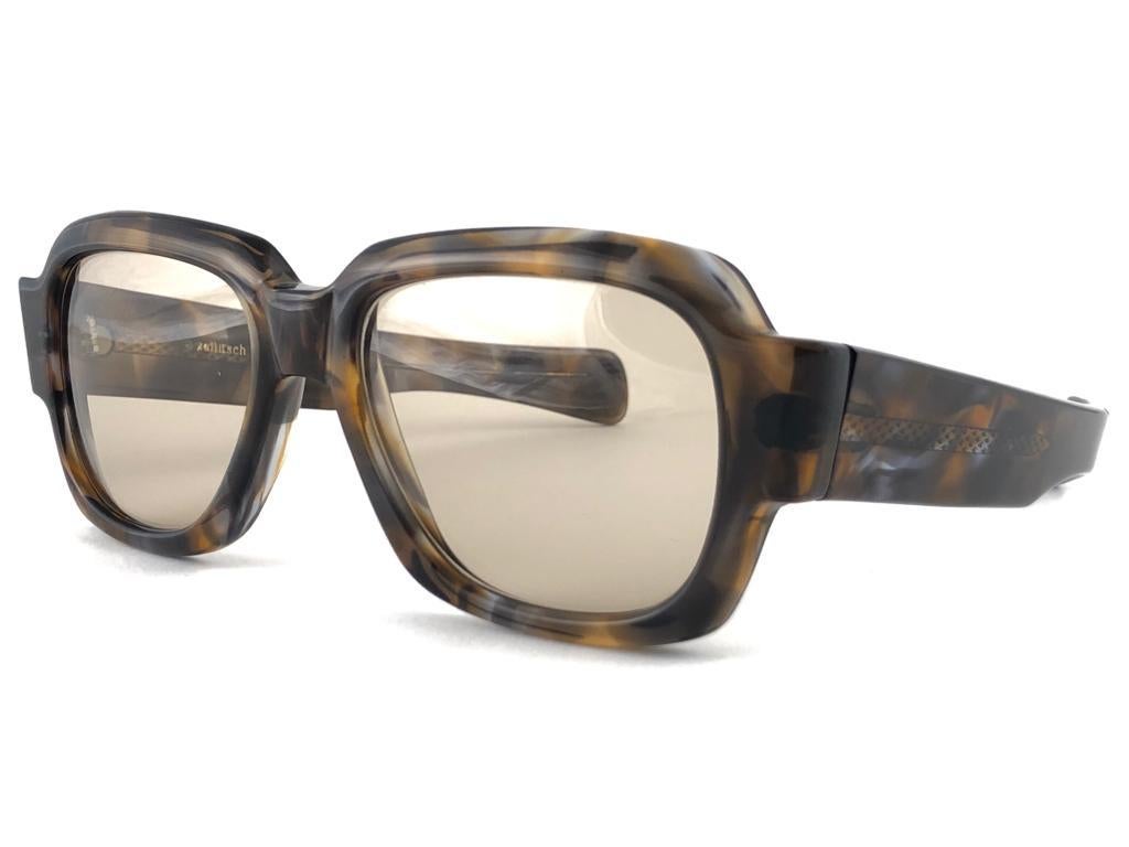 New vintage Zollitsch 217 robust oversized frame. Spotless brown gradient lenses.
This pair have slight wear on them due to to nearly 40 years of storage.  


FRONT : 14.5 CM
LENS  HEIGHT : 4.2 CMS
LENS WIDTH : 5.2 CMS
TEMPLES : 13.5 CMS

