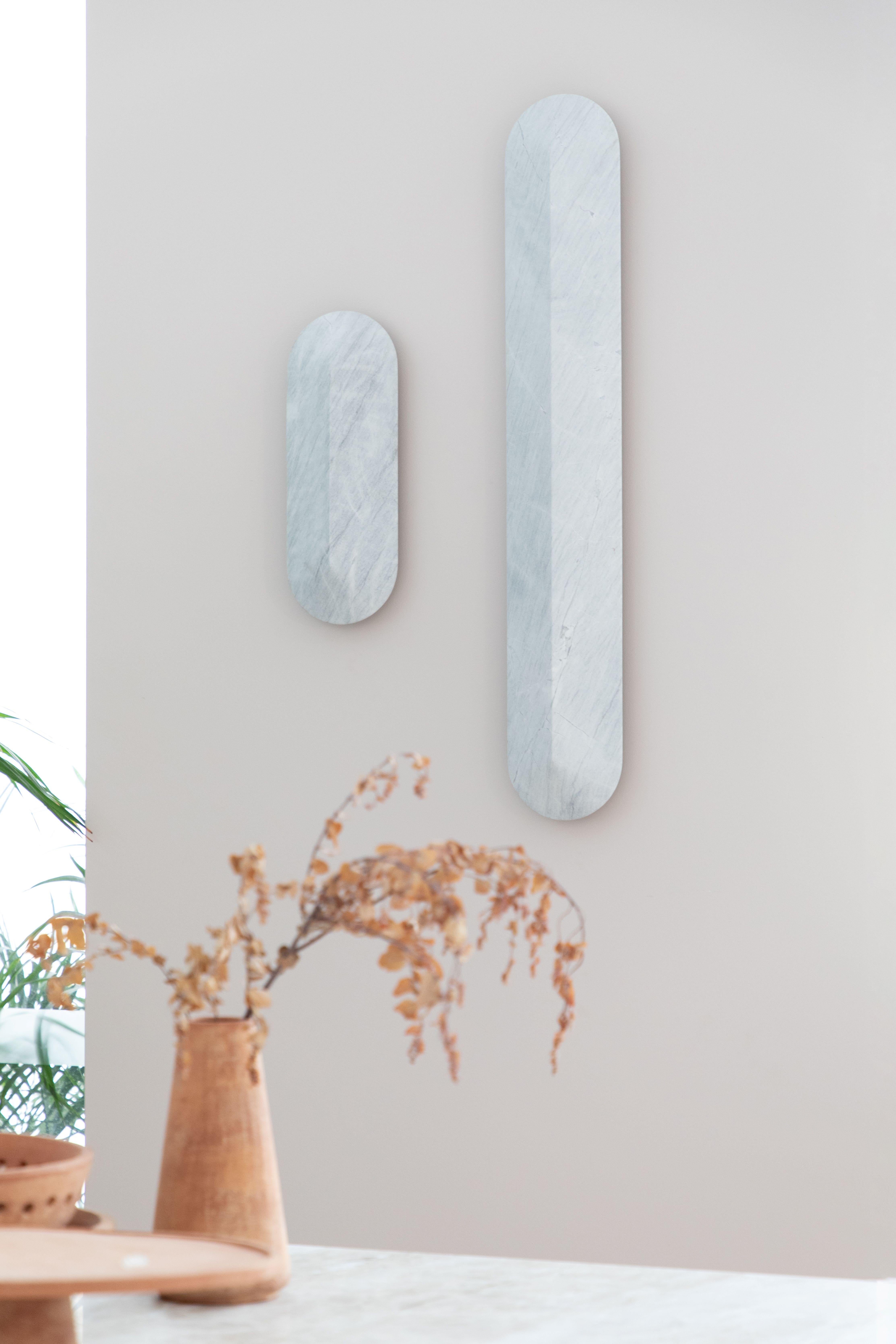 An elegant, elongated wall light, offered in two lengths – 400 millimetres and 900 millimetres. Its shield-like form is characterised by a central sharp line or ‘pinch’ that allows light to fall differently on each side of the Elba, accentuating the
