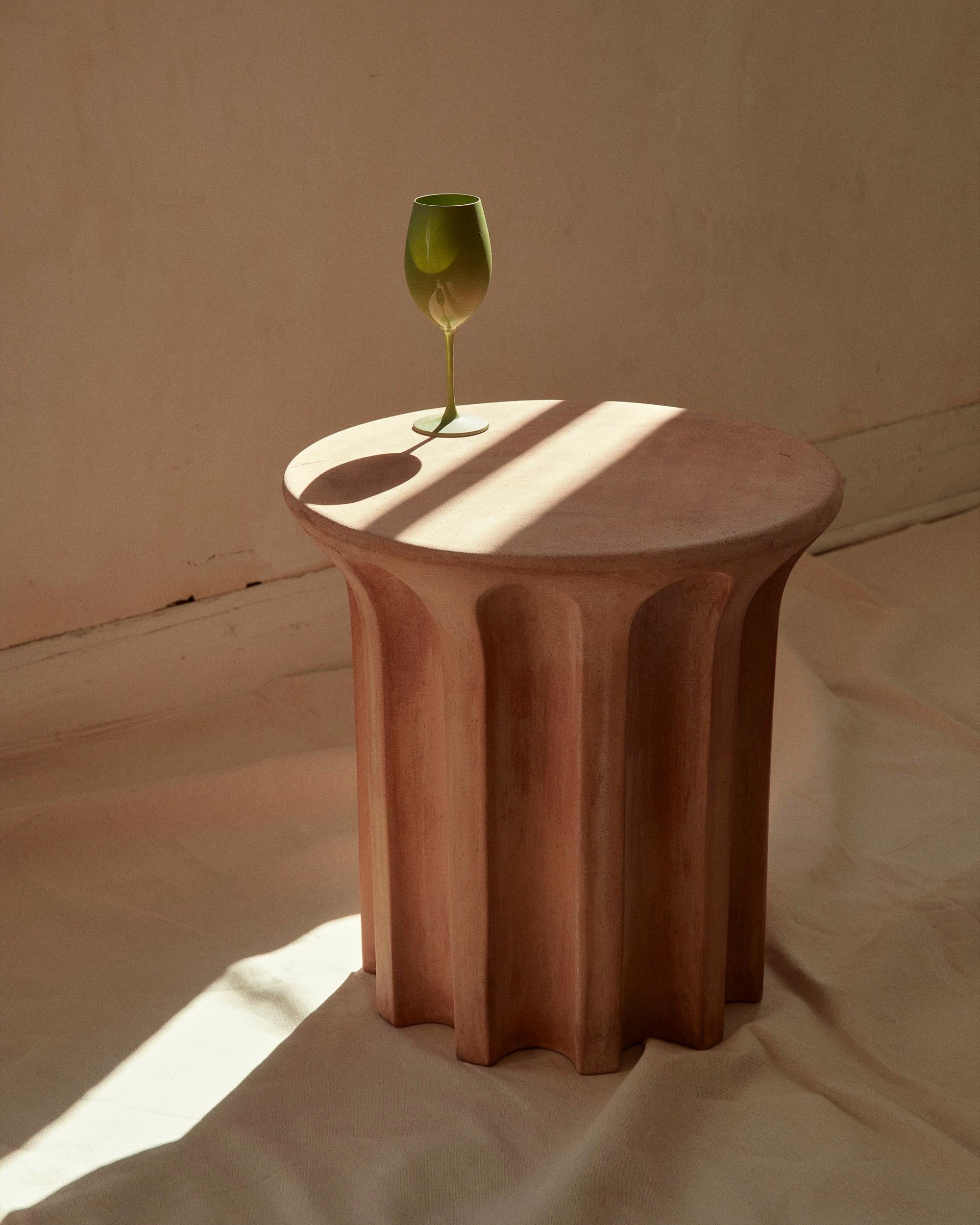A robust terracotta side table featuring a revolving carousel of voids that call to mind the shapes used in architecture and design for centuries. A contemporary exploration of classical form that celebrates the history and legacy of this natural