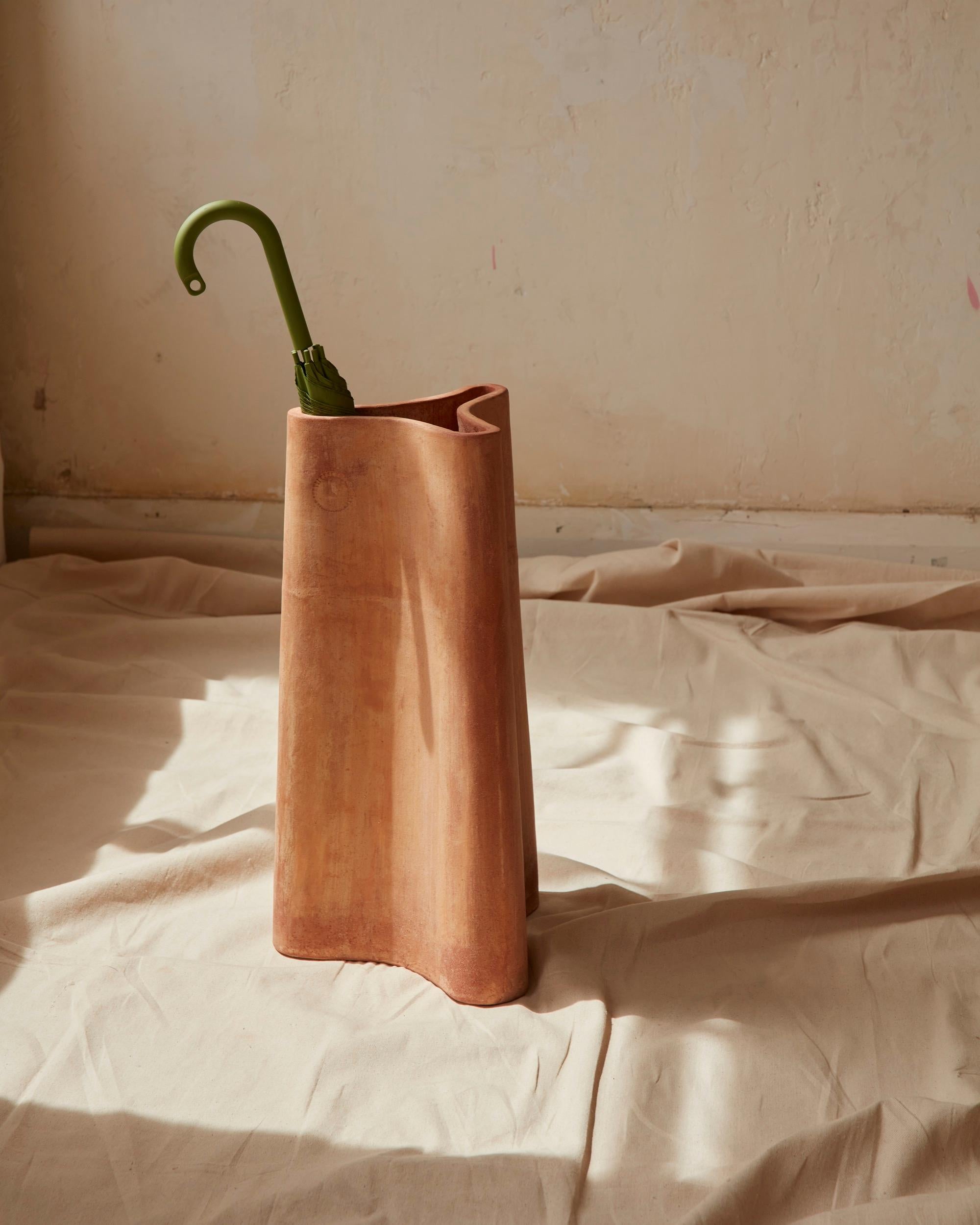 A free-flowing terracotta umbrella holder, inspired by the ribbed oil and water jars of Greece. The three-part, compartment-like form is tapered for stability and form-ribbed for strength.

Included in the range is a smaller vase version, along