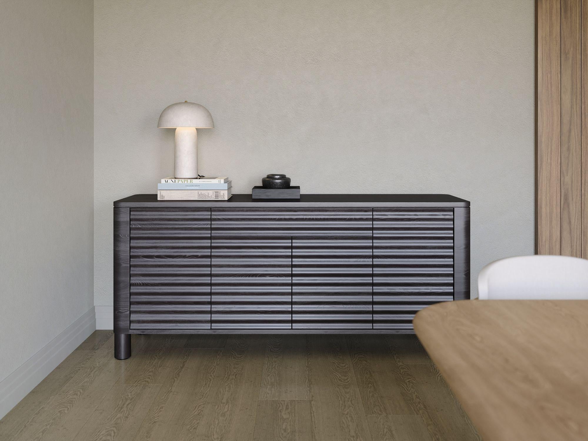 FR Portes et façades ondulées, forme arrondie, absence de poignées, esthétique minimaliste et caractère accentué de l'essence de bois - tout cela caractérise le buffet NEW WEST. Présenté en chêne noir, ce meuble s'intègre facilement dans les