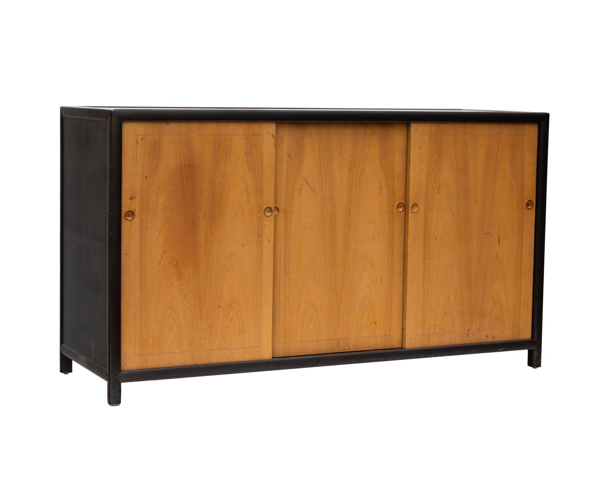 USA, 1950s
'New World' buffet with ebonized case and walnut triple bypass doors designed by Michael Taylor for Baker Furniture. Each side has two removable fixed position shelves and the center a bank of black lacquered drawers with open storage