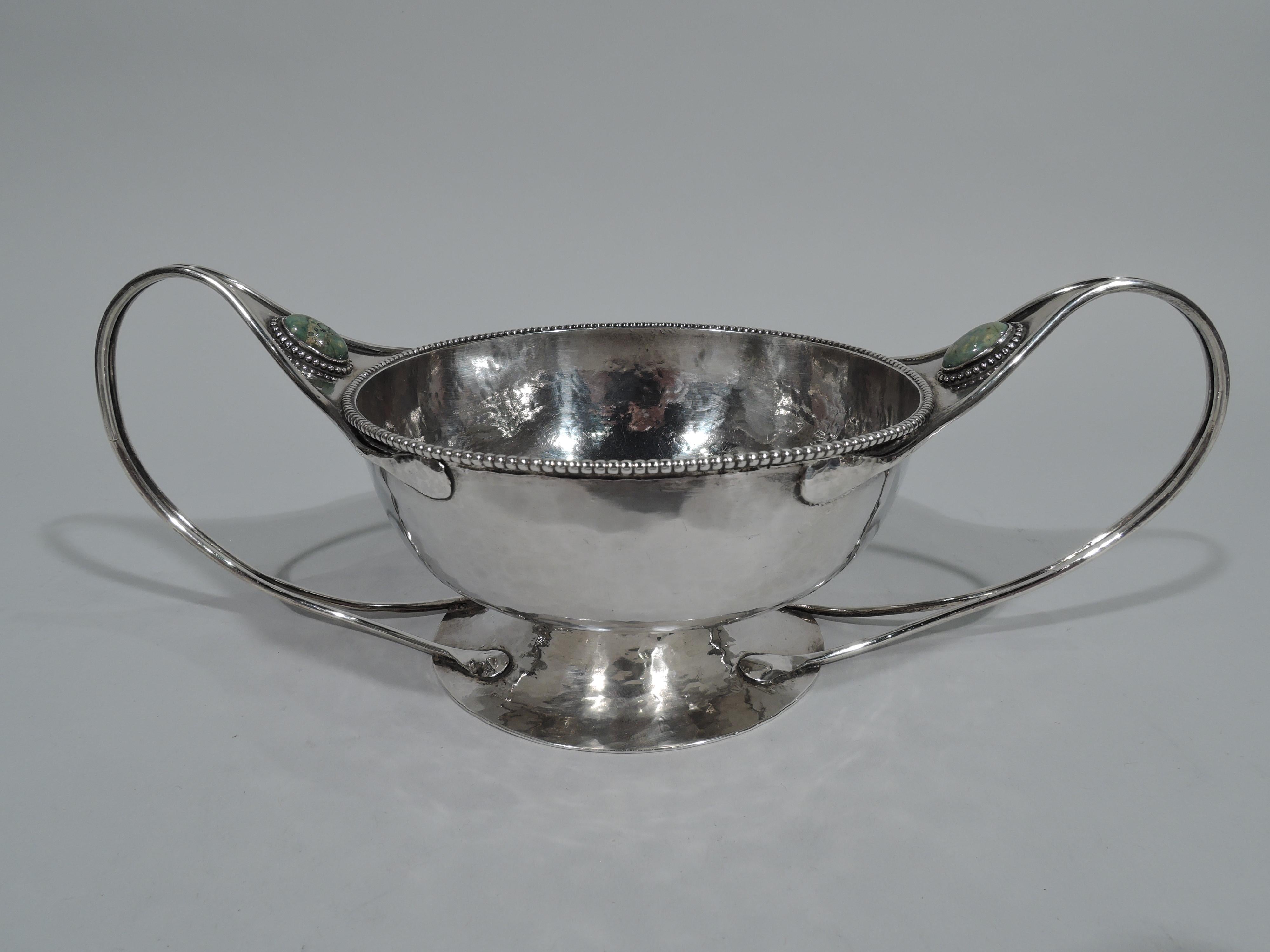 Art & Crafts sterling silver bowl in style of Charles Ashbee. Round with beaded rim and curved sides, and raised and spread foot. Elongated side handles with attenuated split mount and oval cabochon agate bordered by beading. Bowl and foot have