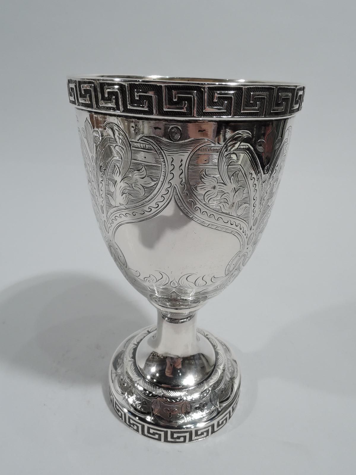 Classical coin silver goblet. Made by William Gale & Son in New York, ca 1860. Oval bowl on columnar stem mounted to domed foot. Engraved leafing scrolls in scrolled strapwork frames on lined ground. One frame vacant. Raised fretwork rims. Bowl