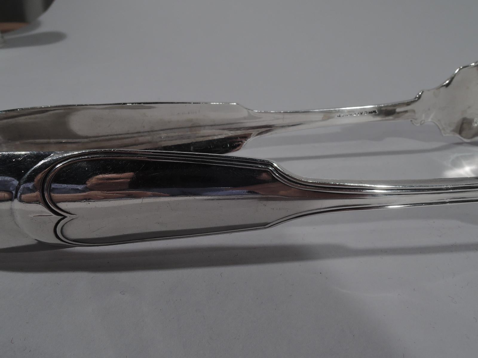 Classical coin silver serving tongs. Made by William Gale & Son in New York. U-form with traditional English double-scroll terminal on each side and scalloped shanks. One side has shaped blade with open rectangles; the other side has 3 tines.