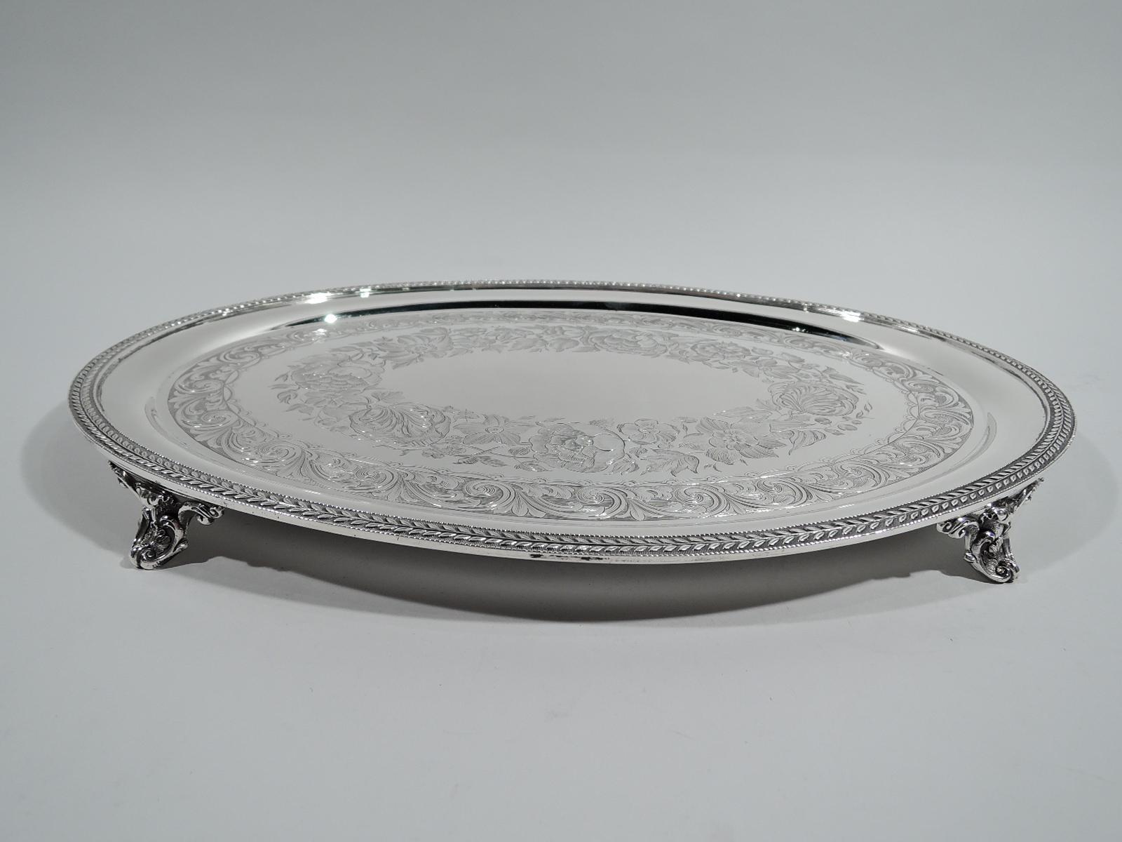 Beautiful Victorian Classical coin silver tray. Made by William Forbes for Ball, Black in New York, ca 1850. Oval well engraved with lushly engraved floral wreath (vacant) and scroll and leaf border. Flat and beaded rim applied with leaf border on