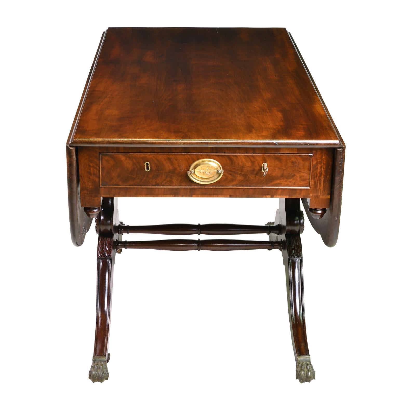 A fine example of an American Federal drop-leaf table in West Indies mahogany, from New York, circa 1810. The solid rectangular top with curved drop-leaves features a beautiful figured grain and is supported by two solid standards in the lyre form