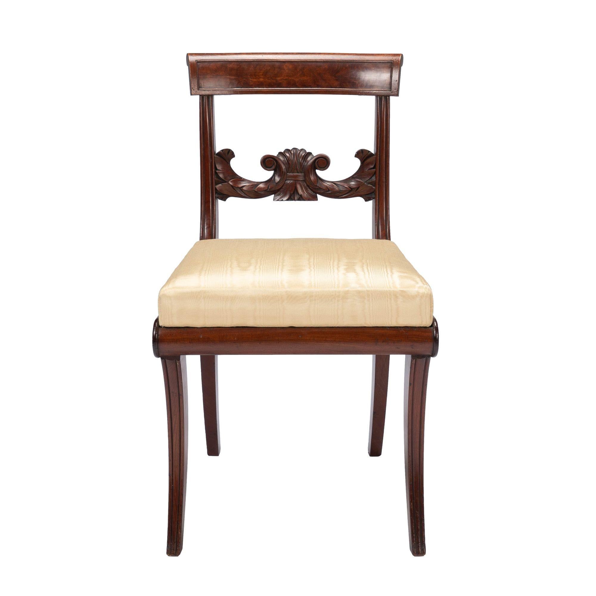 New York Neoclassic klismos form side chair in Honduran mahogany with upholstered box seat. The chair stands on four sabre legs morticed to a mahogany seat frame and fitted with an upholstered box seat. The rear legs continue upward to form the back