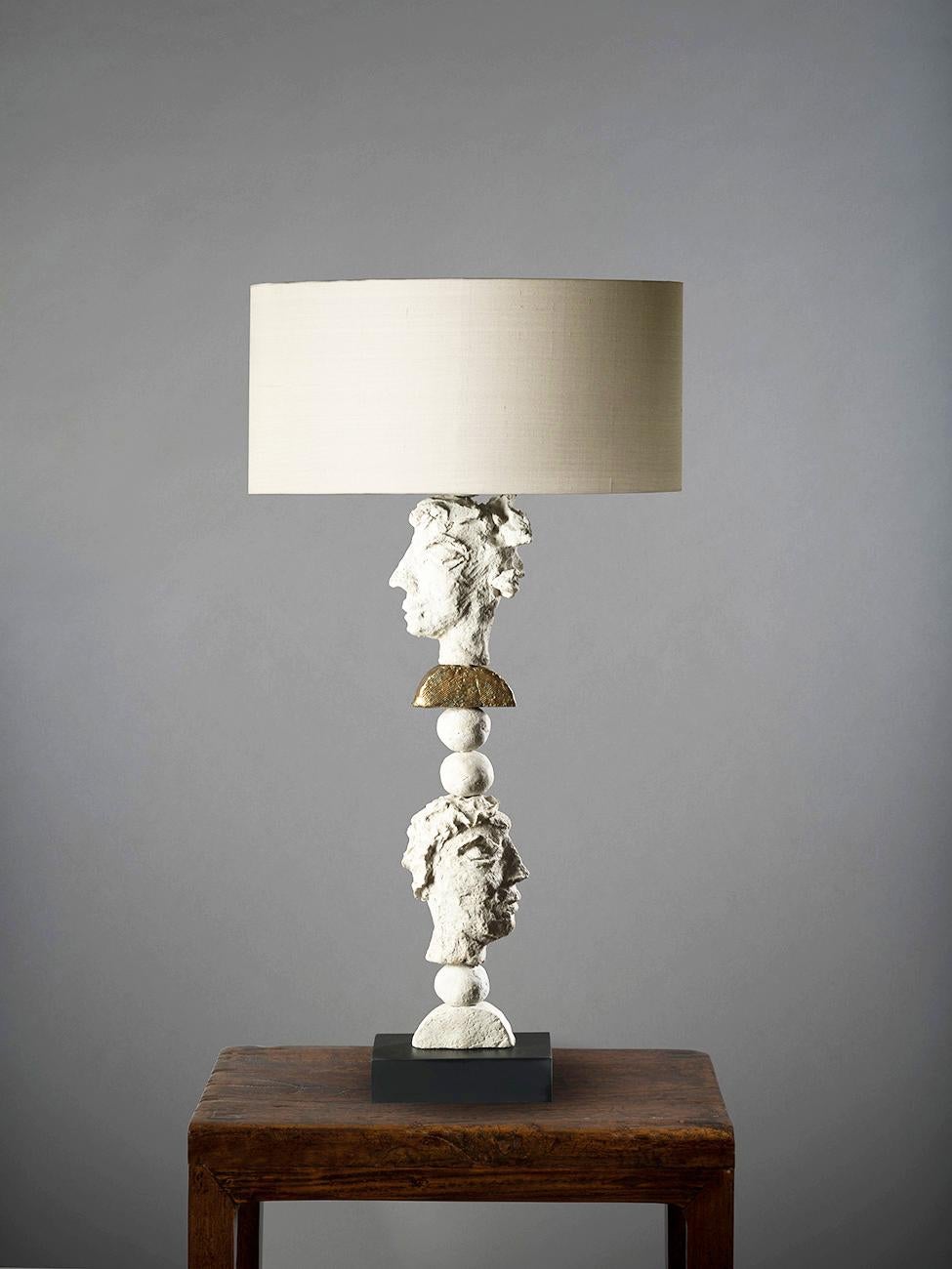 This contemporary Margit Wittig table lamp sits on a rectangular slate base and features multiple white resin handcrafted spheres and semi-circles with organic surface textures. A single central semicircle is enveloped in 24-karat gold leaf, done by