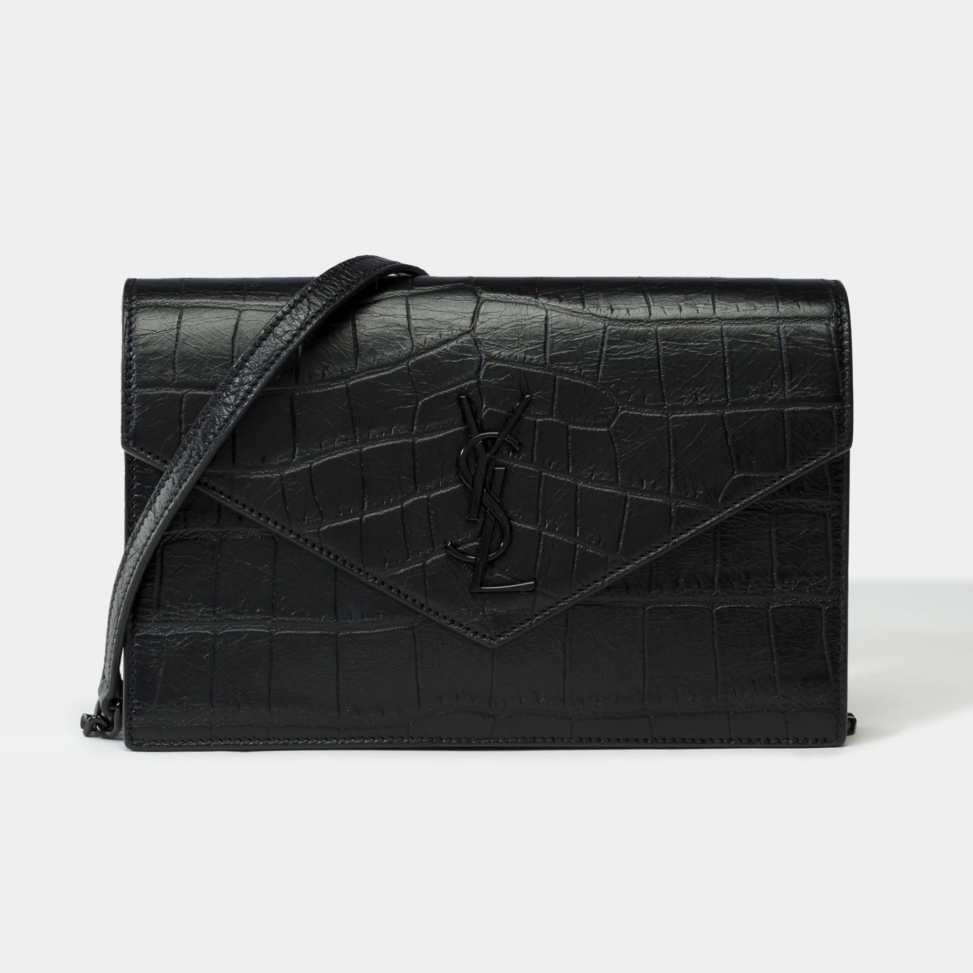Stunning​ ​YSL​ ​​ ​Wallet​ ​On​ ​Chain​ ​(WOC)​ ​Enveloppe​ ​in​ ​black​ ​leather​ ​printed​ ​crocodile​ ​chain​ ​decorated​ ​with​ ​black​ ​Cassandra,​ ​black​ ​metal​ ​trim​ ​allowing​ ​a​ ​shoulder​ ​or​ ​crossbody carry

Snap​ ​closure
Black​