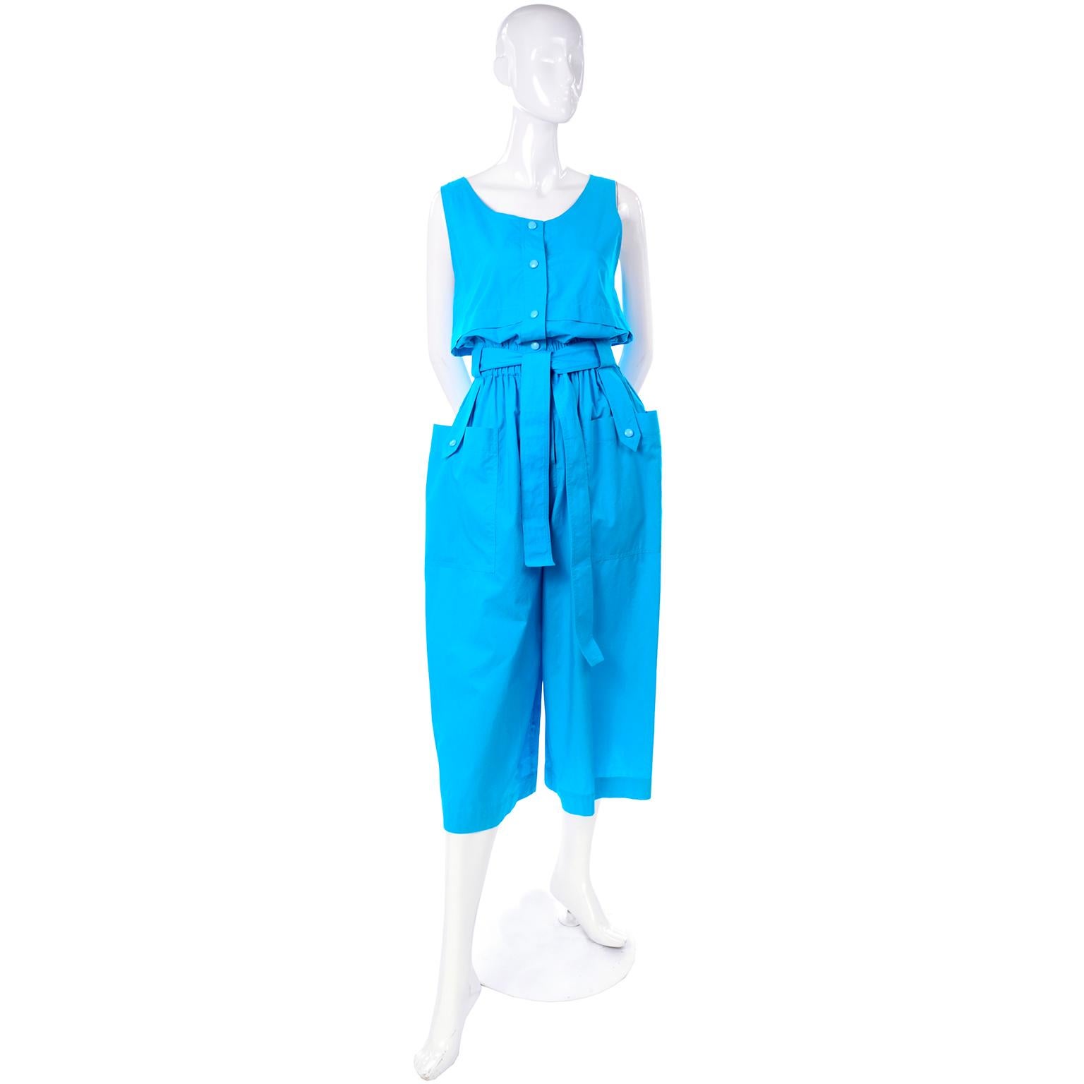 This is a gorgeous deadstock bright blue cotton jumpsuit from Yves Saint Laurent. This great 1980's  jumpsuit has a flap over the bust, elastic waist with fabric waist tie, and large patch pockets on the front of the legs with little button flaps!