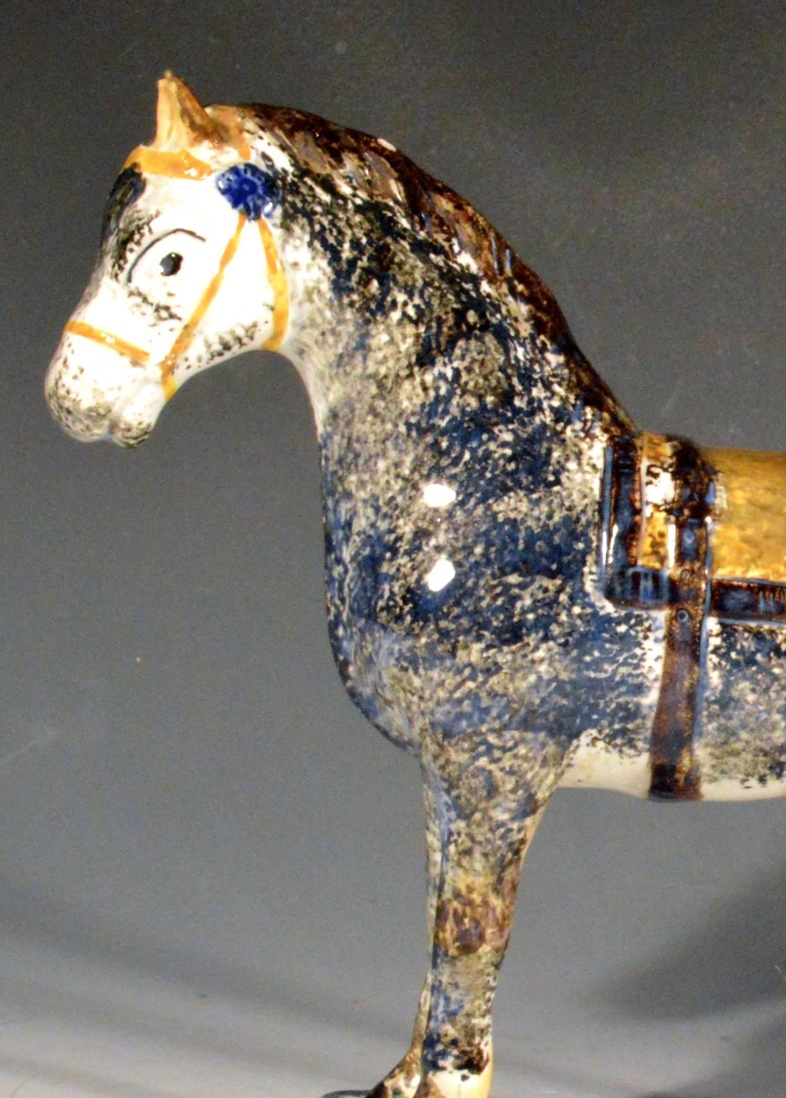 Newcastle Prattware Pottery model of a horse, 
St. Anthony Pottery, Newcastle upon Tyne,
circa 1800-1820.

The horse with cropped tail stands on a flat mottled green shaped rectangular base. It has an unusual coloring of mottled red and cream