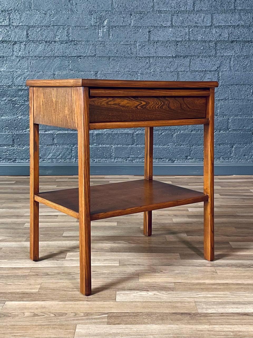 Condit: Rifinito con perizia 
Materiali: Legno di olmo tinto noce, piano in legno di noce

Questo comodino Mid-Century Modern degli anni '50, sapientemente rifinito, mostra un'artigianalità senza tempo con linee pulite e una pratica funzionalità.