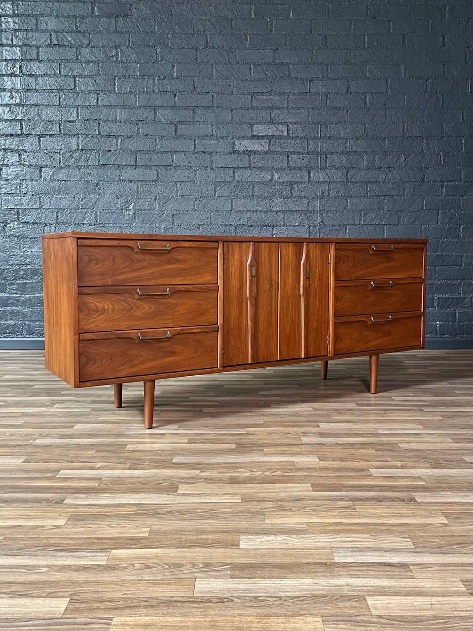 Condit: Rifinito con perizia

Questa bella cassettiera moderna di metà secolo, attribuita a Barker Bros, presenta una raffinata finitura in noce e un'accurata disposizione di sei cassetti e ante centrali. La venatura del noce abbinata ai cassetti e