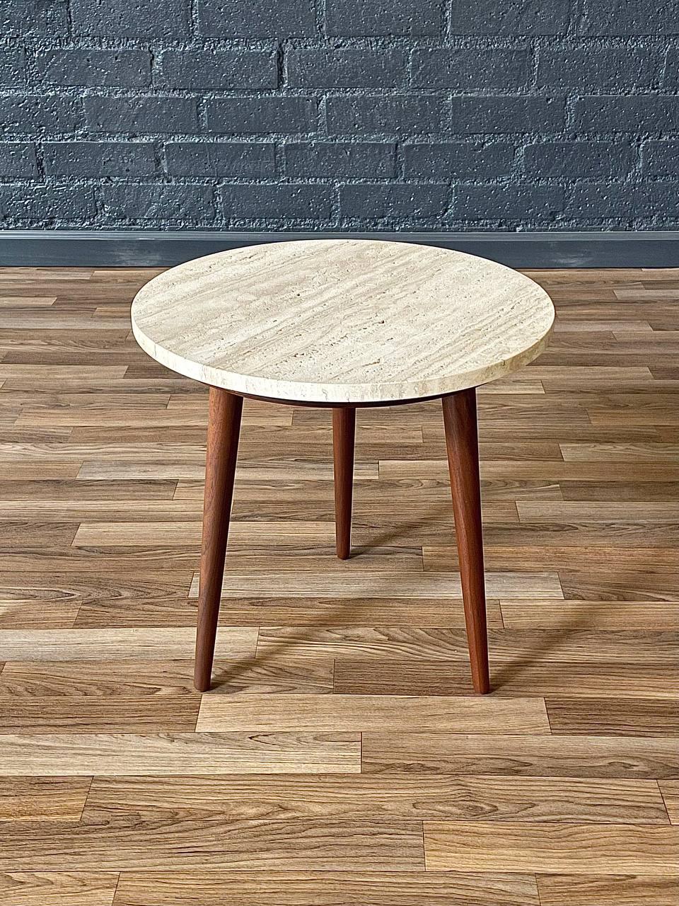 Cette table d'appoint tripode en noyer datant du milieu du siècle dernier et datant des années 1960 présente un superbe plateau en marbre travertin aux tons beiges chauds et aux veines naturelles. Les pieds en noyer massif, élégamment fuselés,