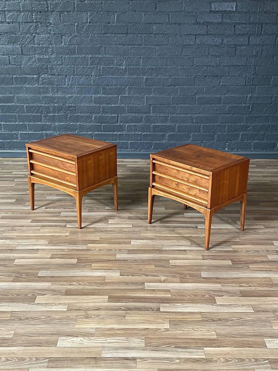 Crafted by Lane in the 1950s, this exquisite pair of Mid-Century Modern “Rhythm” nightstands showcases the clean lines and sculptural elegance that define the era. Constructed from rich walnut, they feature sculpted drawer pulls and gently tapered