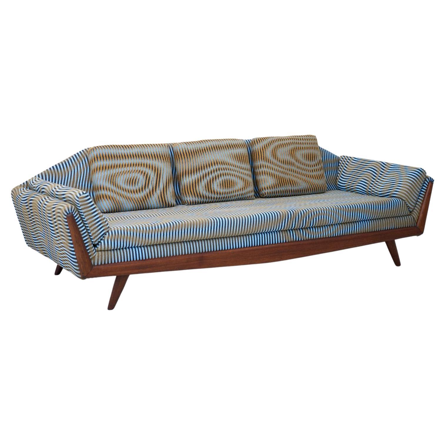 Dieses schöne Sofa wurde von dem Berliner Textilstudio Case Studies neu mit einem maßgeschneiderten Stoff bezogen. Die geschnitzten Holzbeine und die ausgeschnittene Rückenlehne machen den Reiz dieses skulpturalen Sofas 