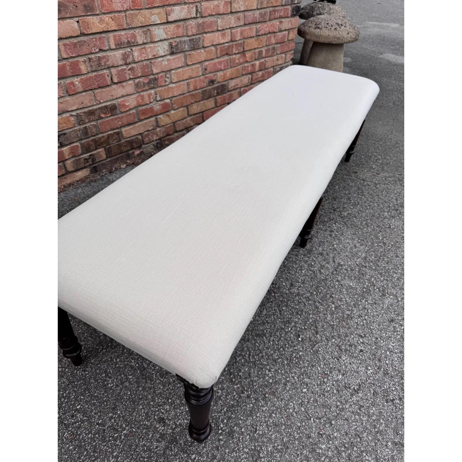 ¡Precioso banco antiguo recién tapizado! El tejido es un elegante blanco roto de transición. La base tiene 6 bonitas patas torneadas de un intenso color marrón que combina de maravilla con la tela blanca y las cabezas de clavos oscuras. Sería una