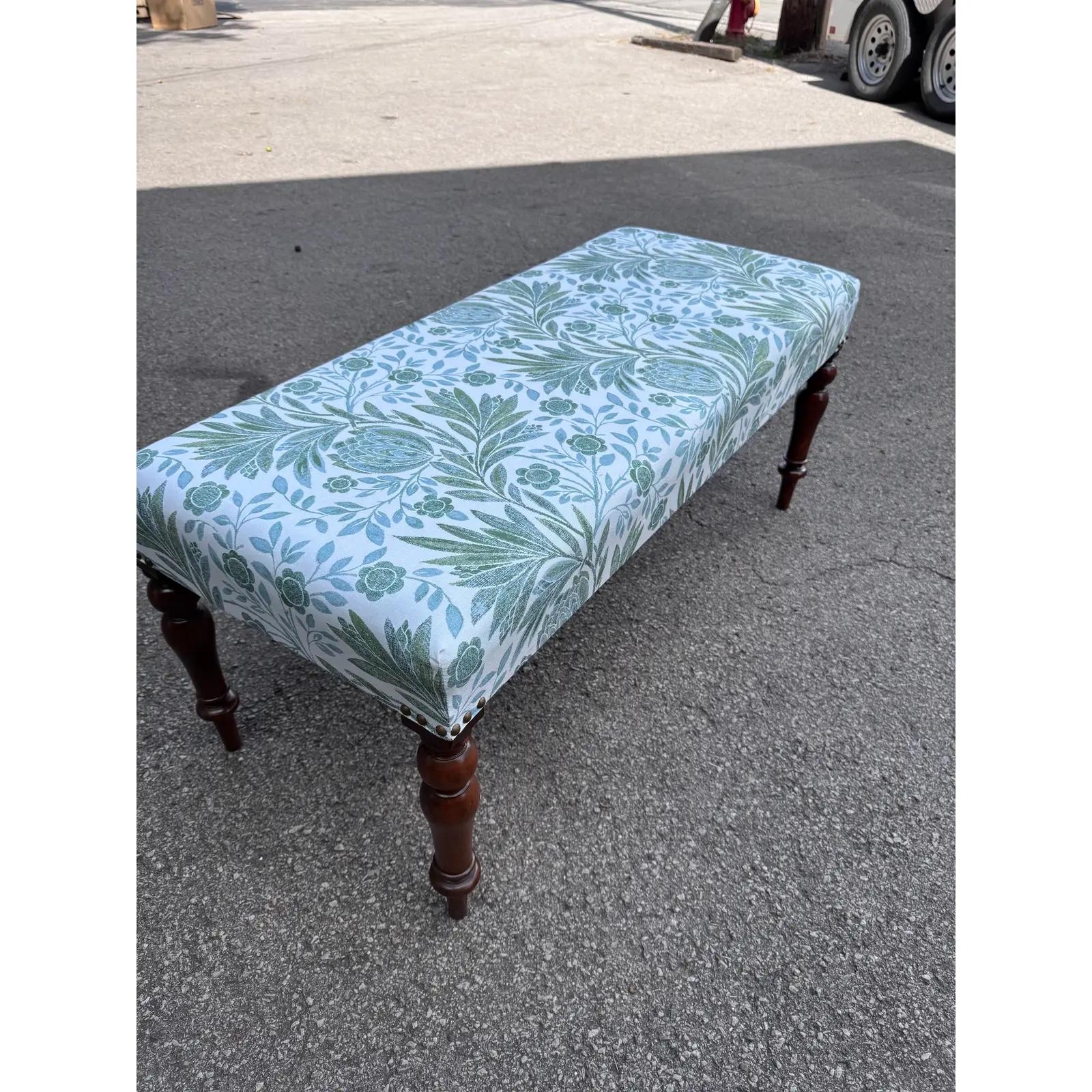 This is a beautiful antique English bench! Newly reupholstered, this bench is in stunning condition. The legs are sturdy and firm, with a lovely patina and hand carved detailing as well as turned design. The new fabric is a lovely blue, green and
