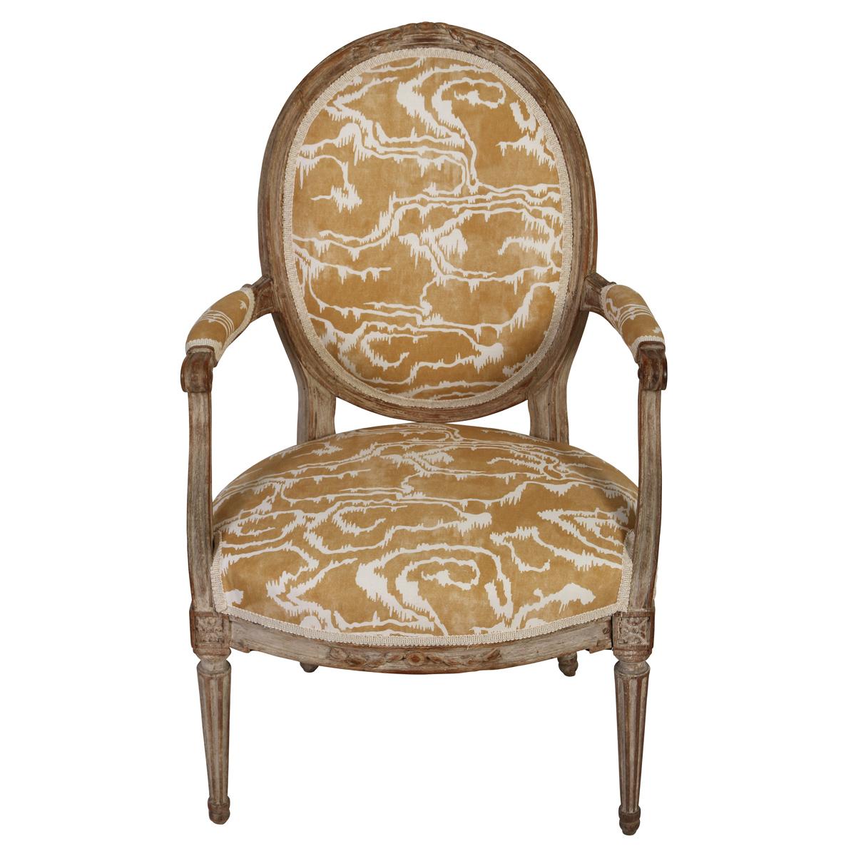 A beautifully updated Louis XVI style armchair that embodies the timeless elegance of 18th-century French design with a modern fabric from Paolo Moschino. Featuring a classic oval back and gracefully fluted legs, the frame is crafted from solid wood