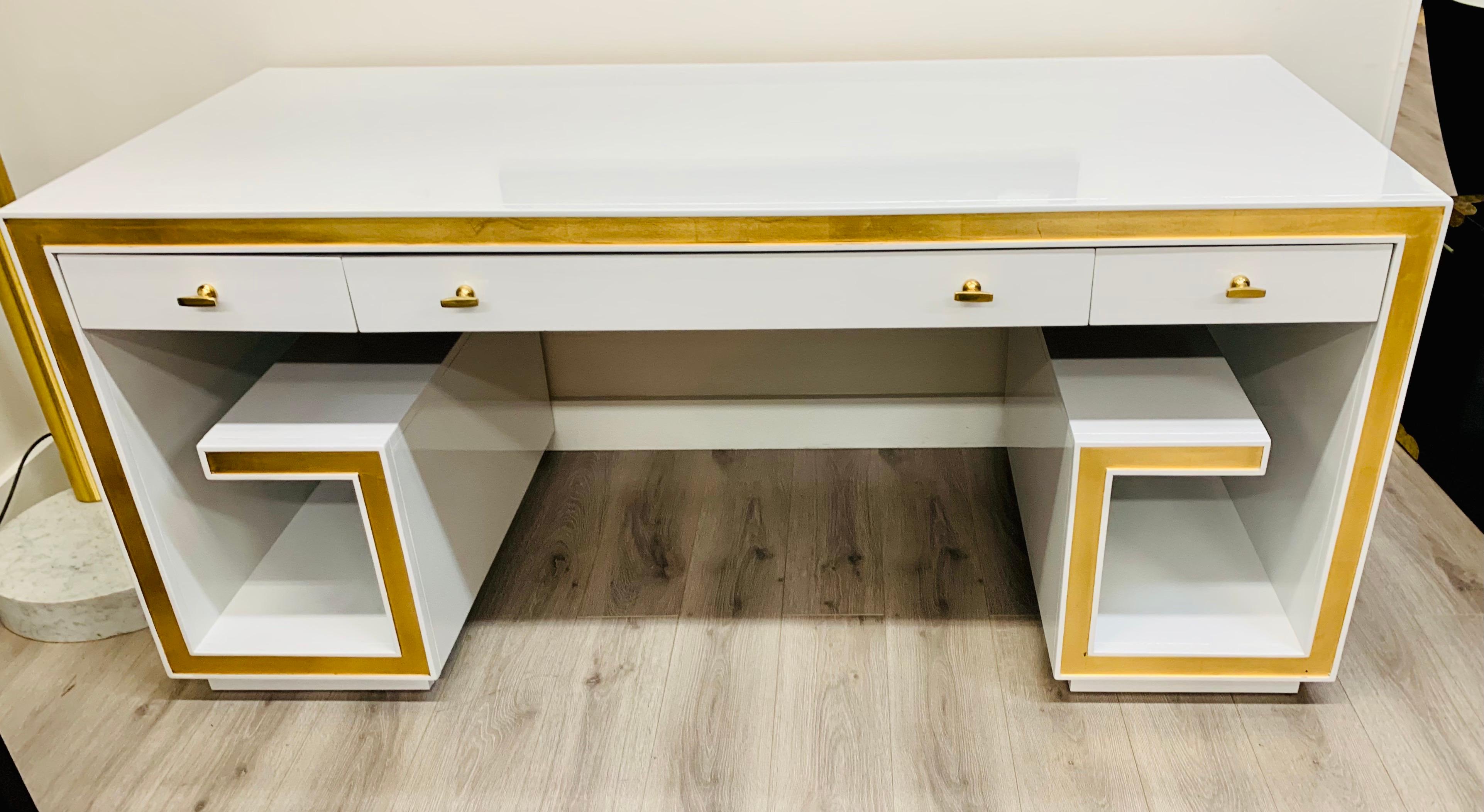 Beautiful three drawer writing desk has been newly lacquered in white with painted gold trim. New brass hardware. Dropfront keyboard drawer in center.