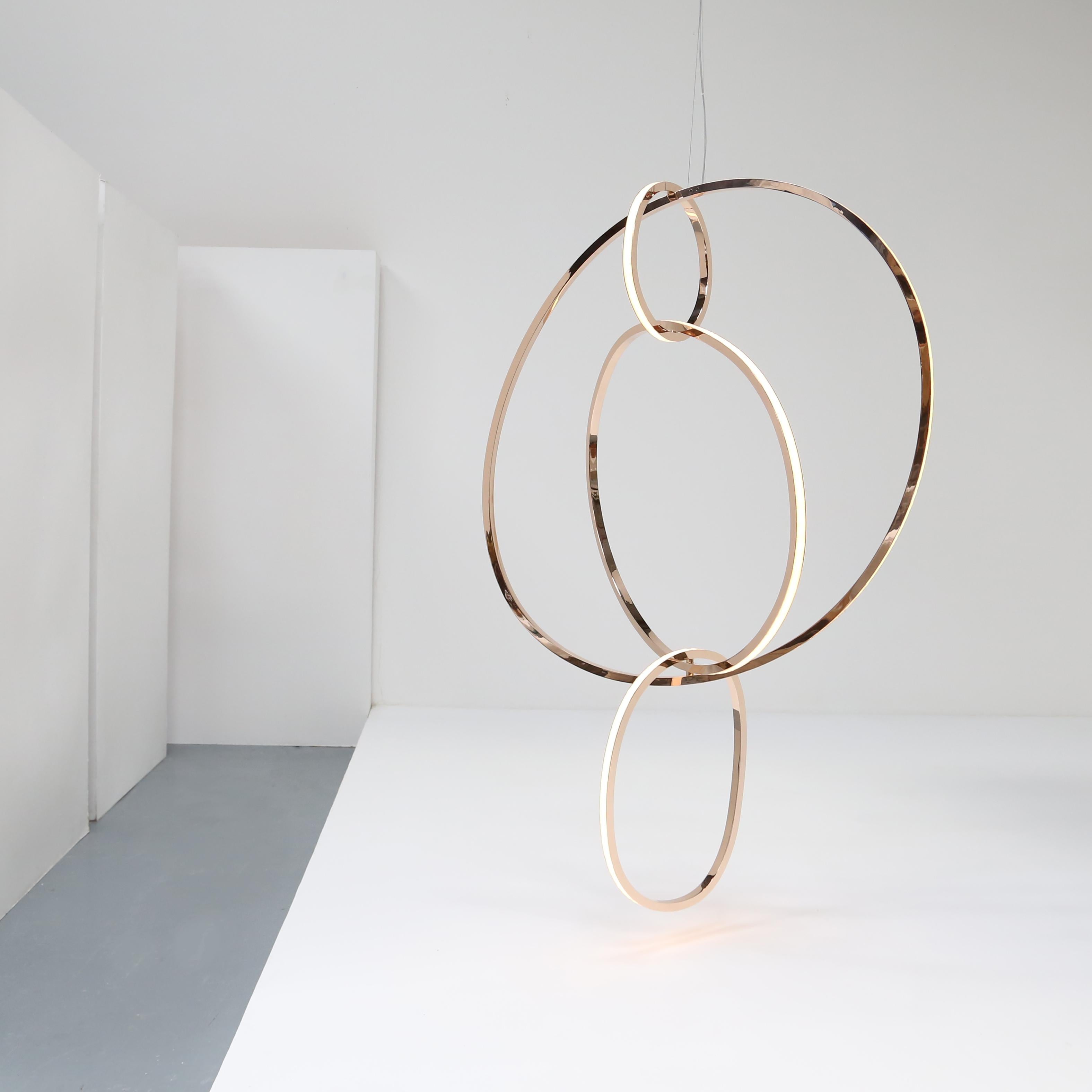 This elegant arrangement of vertically strung rings, made up of solid polished bronze and opal glass sheathed LEDs, is singular in its beauty from each angle a subtly different representation of calm, quiet, stillness that gives forth a warm, soft