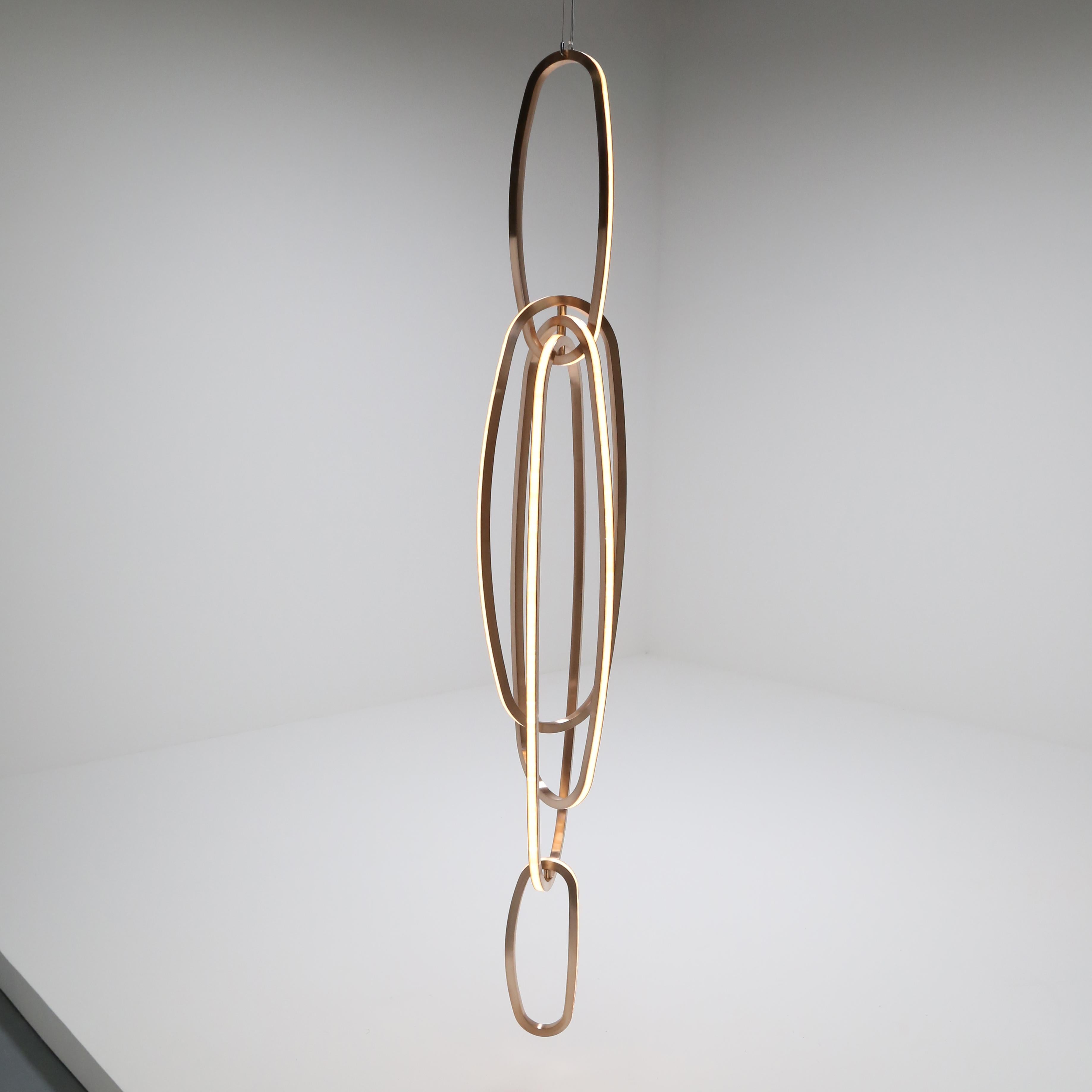 Fouette II, a hanging light sculpture in mirror polished bronze, glass, and LED, is arranged in Barry’s signature composition of interconnected ellipses in this case, uniform in shape, and suggestive, together, of the ballet position from which they