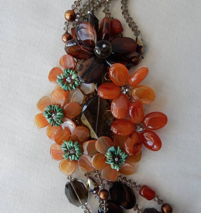 A stunning statement piece handcrafted in rich colors of orange agate flowers accented with turquoise and smoky quartz centers.  Each beaded strand graduates longer than the next, and features stations of multishaped smoky quartz, orange agate, red