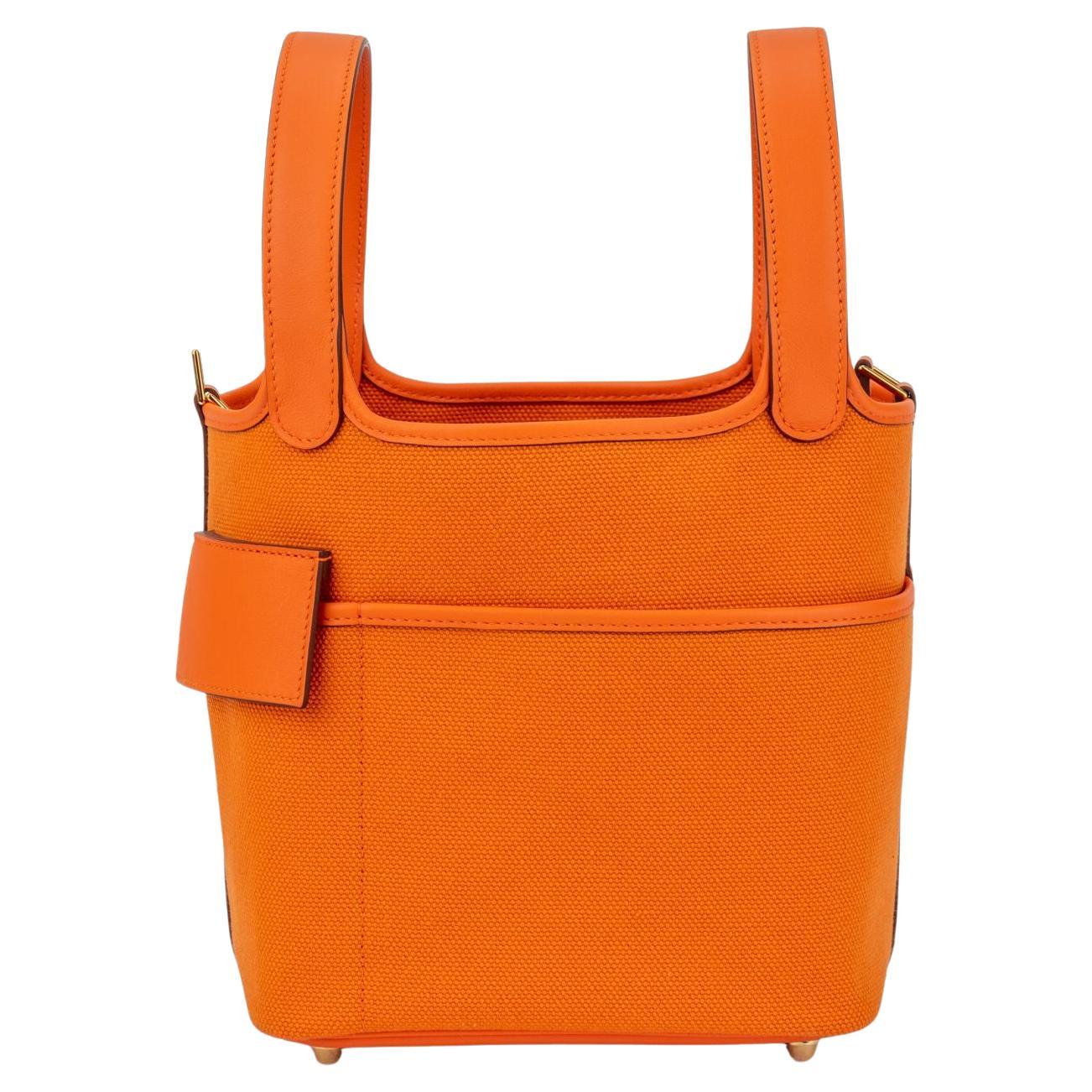 Hermès  new in box Orange Swift and Toile Geoland Cargo Picotin Lock 18,  gold tone hardware . This chic and lovely tote is crafted of sturdy canvas in orange. The bag features looping leather top handles, exterior pockets, and gold tone hardware,