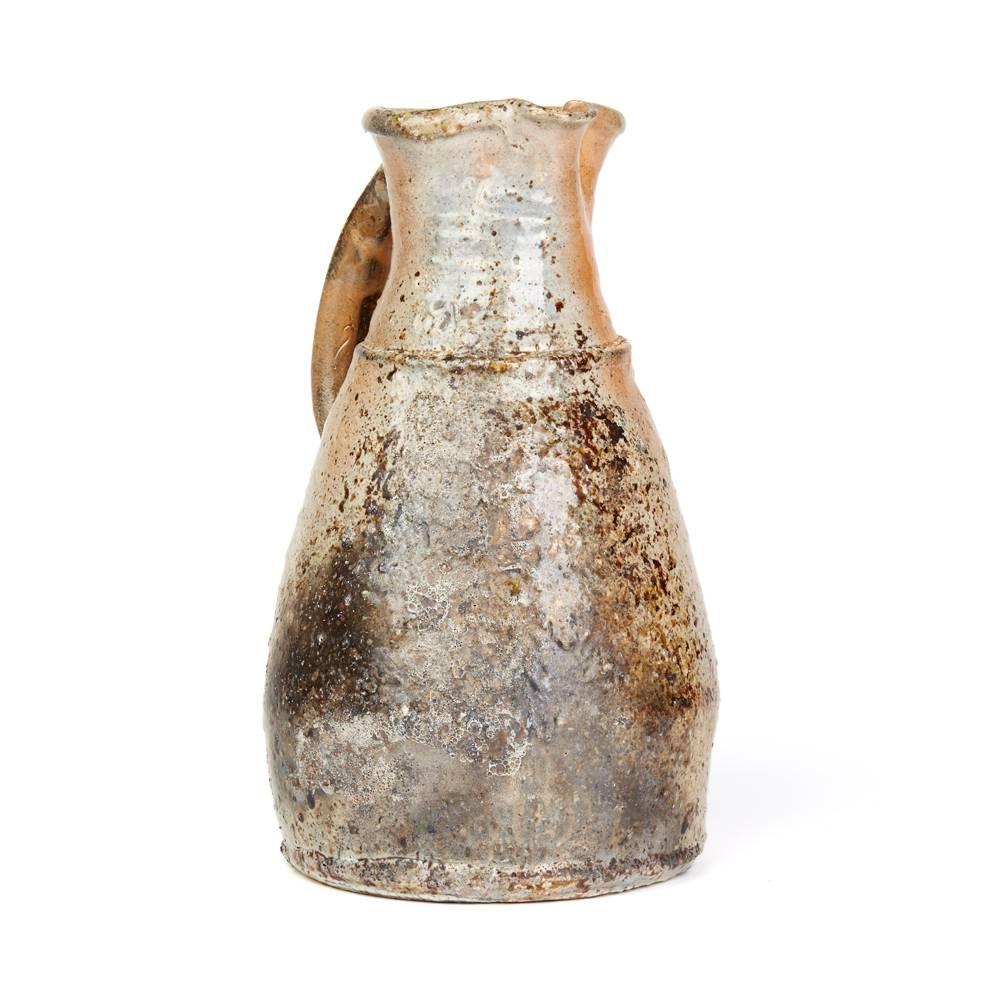A stunning and large vintage British studio pottery jug by renowned potter Nic Collins and made at Powdermills Pottery. This heavily potted stoneware jug has a tapered body narrowing to the top with a loop handle attached to the neck. The jug is