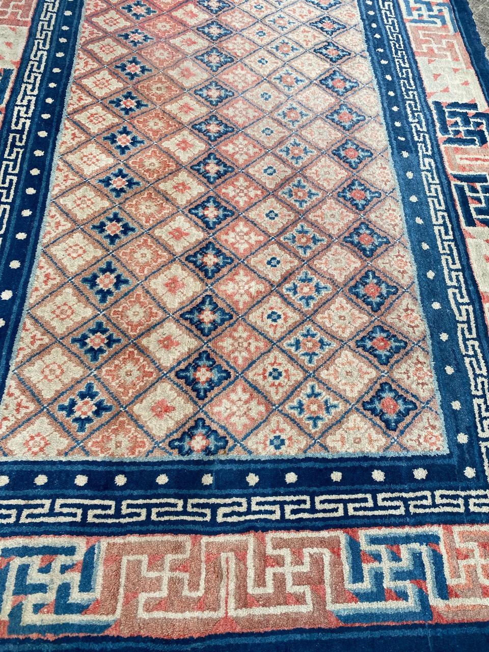 Exquisite antique Chinese rug from Ningxia. Stunning geometrical design featuring small diamond-shaped motifs with stylized floral patterns in a palette of blue, pink, orange, and white. The border showcases a pink background with overlapping line