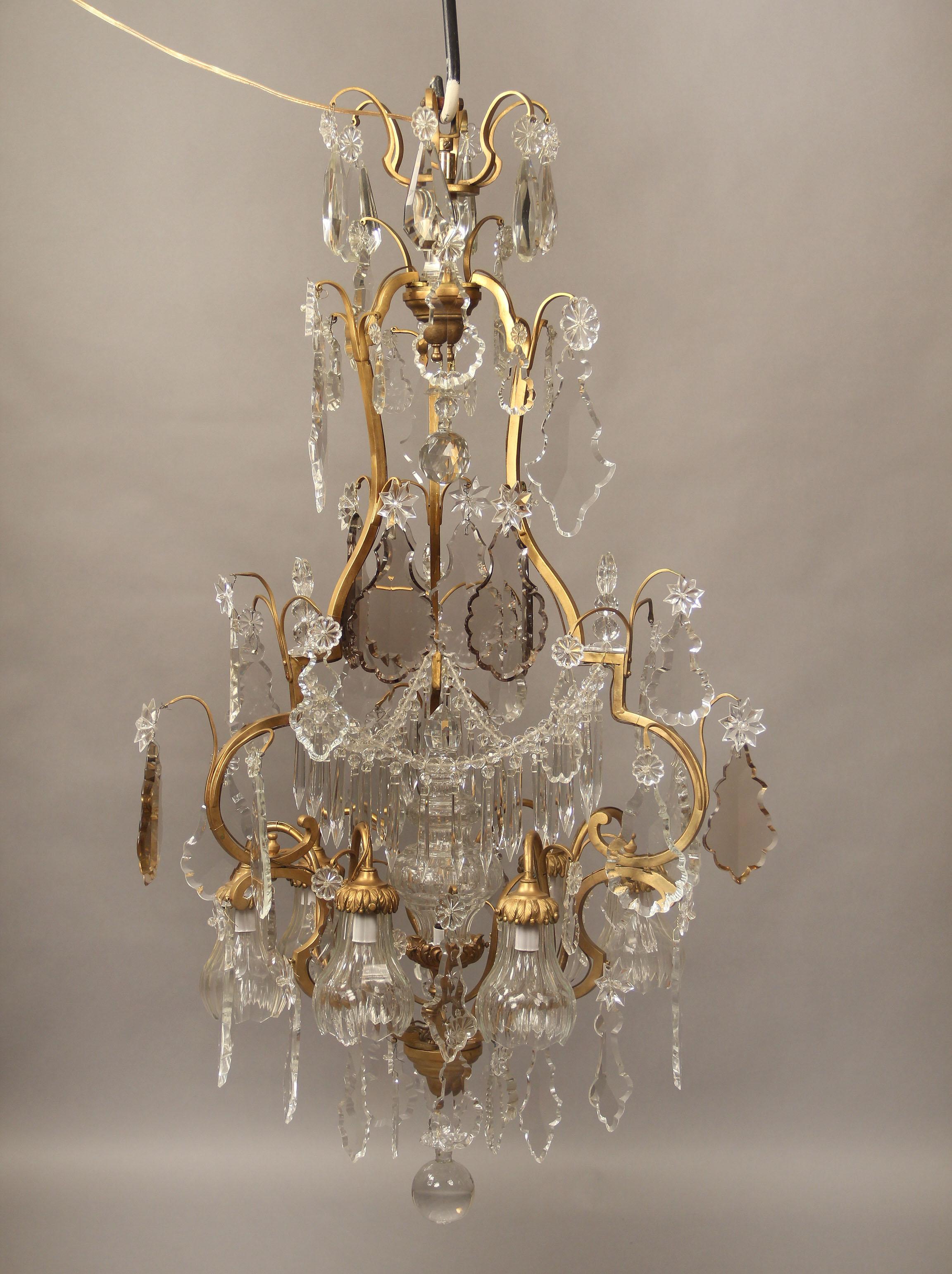 Un beau lustre à neuf lumières en bronze doré et cristal du début du 20e siècle.

Cristal à facettes et formes multiples, guirlandes perlées le long du corps, lance centrale éclairée à l'intérieur, huit lumières périphériques.

Si vous cherchez