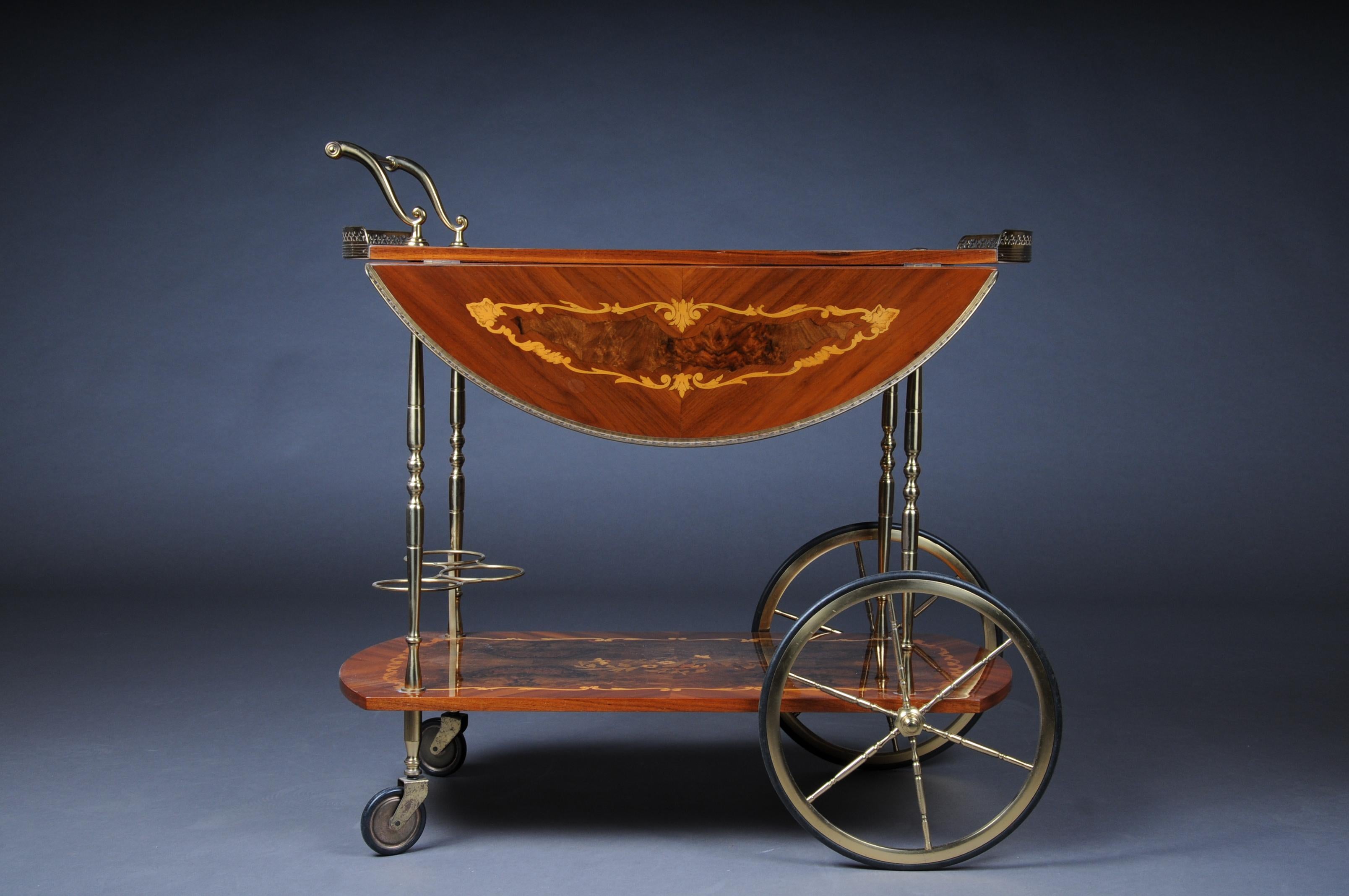 Nice Italian bar trolley / serving trolley, inlaid.

Solid wood veneered and inlaid. Two floors with brass. Foldable pages.
2 tier storage on 4 castor feet.

(V-230).