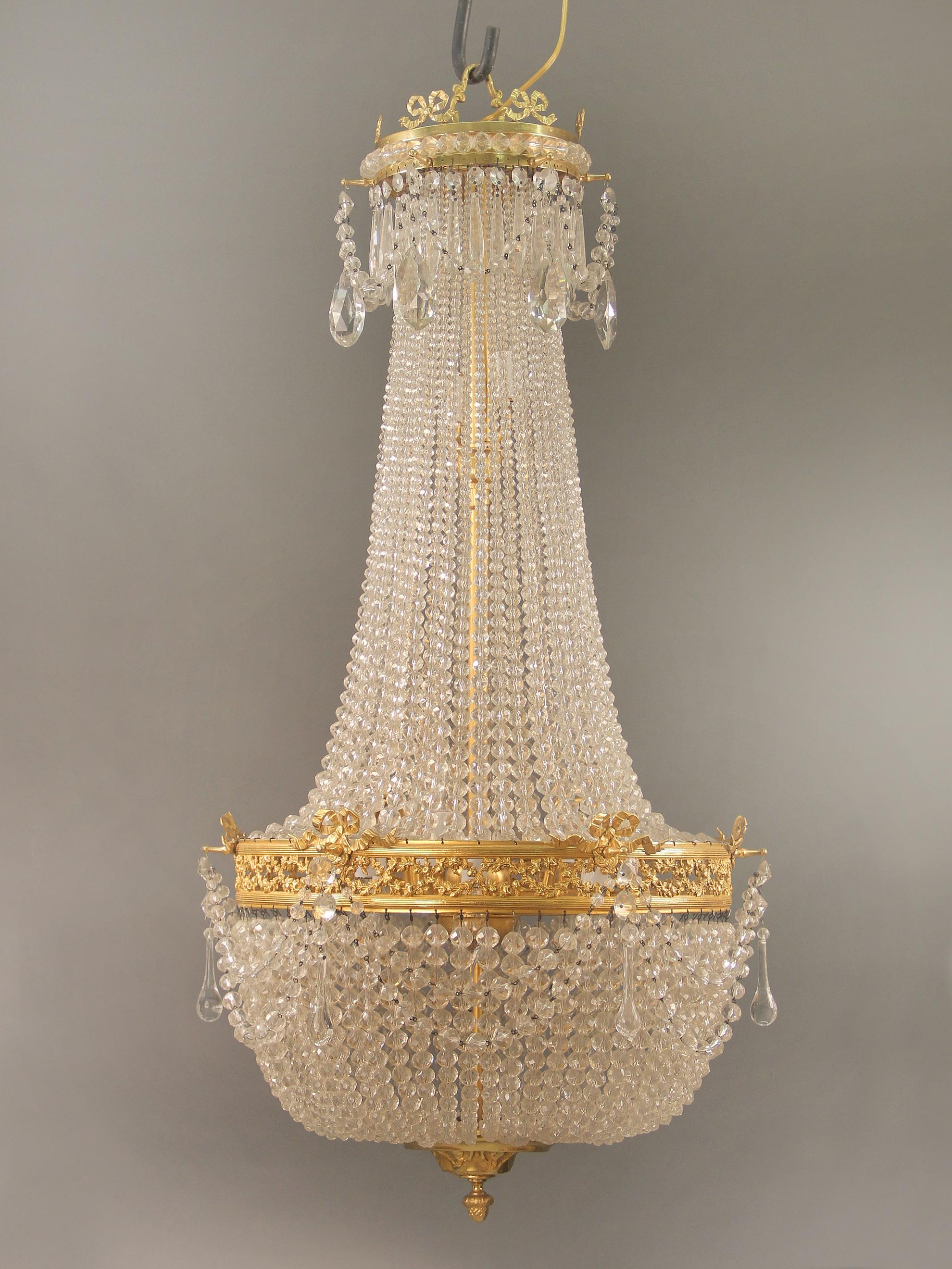 Lustre à onze lumières en bronze doré avec panier perlé de la fin du 19e siècle

La couronne est ornée de nœuds de bronze surmontant des cristaux en goutte d'eau et des guirlandes de perles. Les perles sont reliées à une frise de guirlandes
