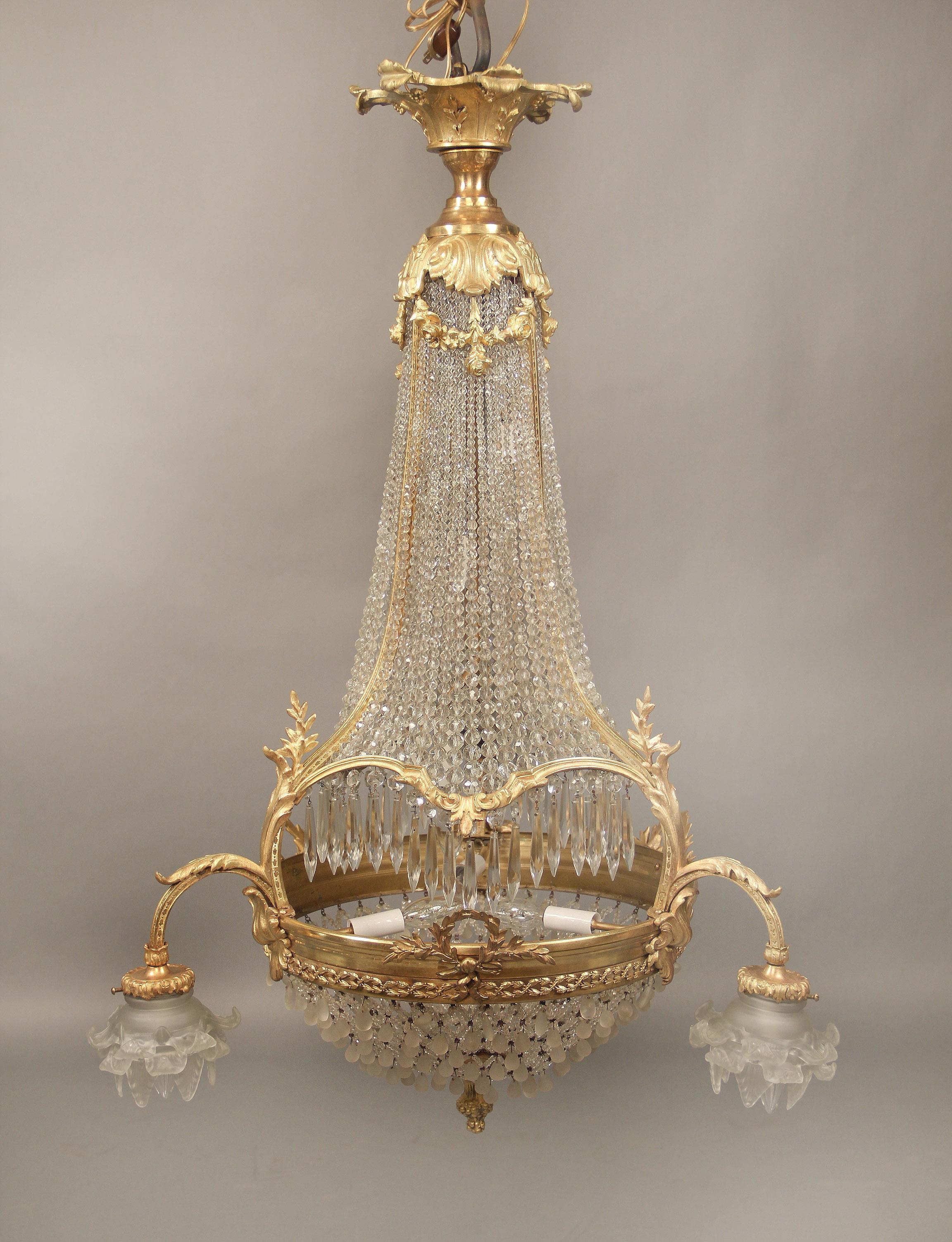 A nice late 19th century gilt bronze beaded basket nine-light chandelier.

The upper and lower part of the cage connected by bronze straps, the top with floral designs, the bottom with wreaths and three arms with rose shades, six tiered interior