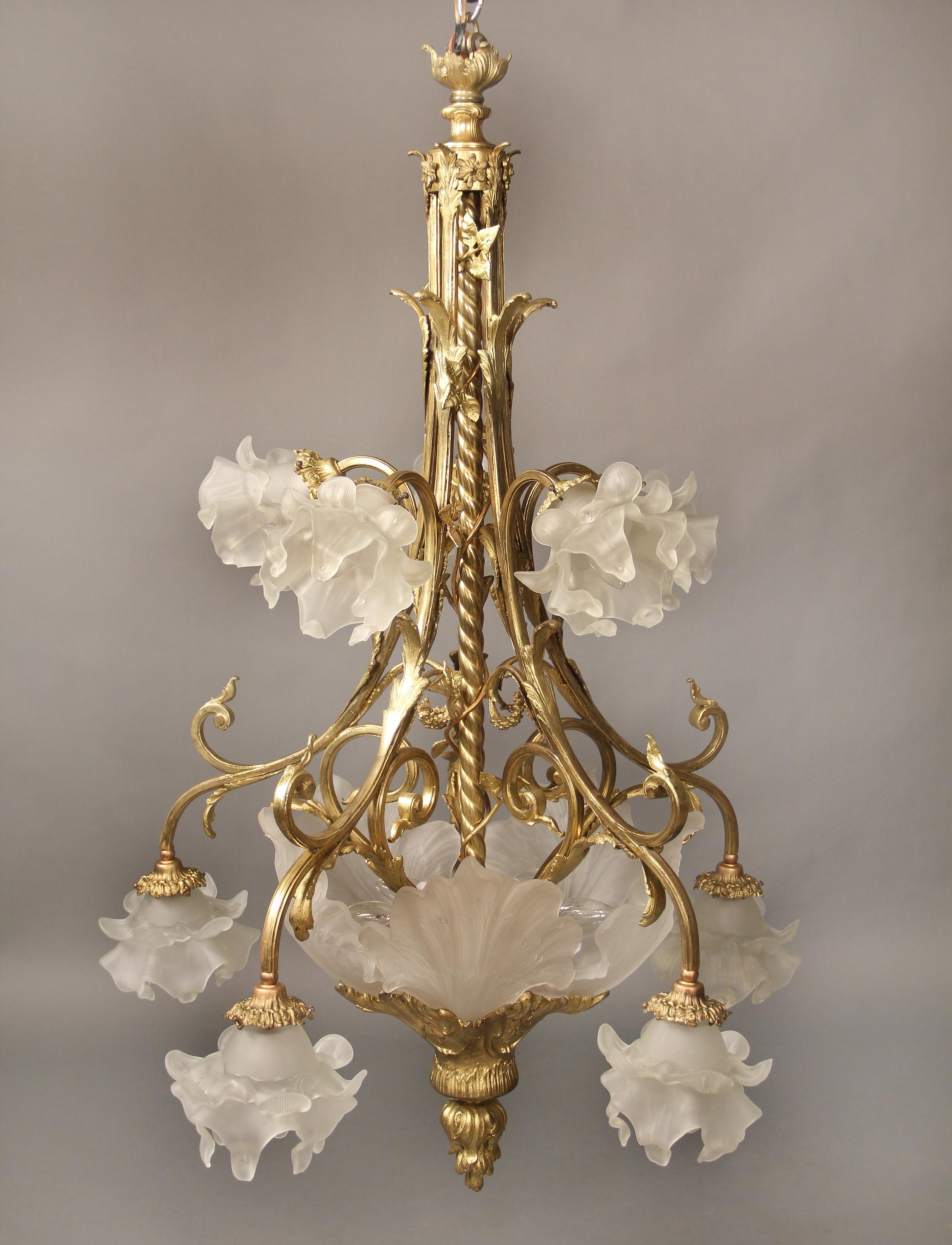A nice late 19th century gilt bronze fifteen light chandelier

Bronze floral frame designed with a twisted rope running down the center, the bottom surrounded with frosted shell shaped shades with a flame tip base, ten tiered perimeter lights with
