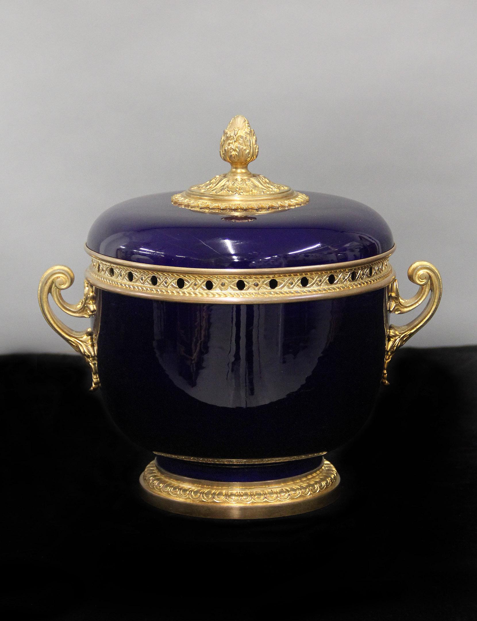 Joli centre de table en porcelaine de Sèvres monté en bronze doré de la fin du 19e siècle

Le grand bol à pot-pourri bleu cobalt et le sommet monté avec un bouchon et un gland en bronze, des poignées décorées de feuillage de chaque côté.

À la fin