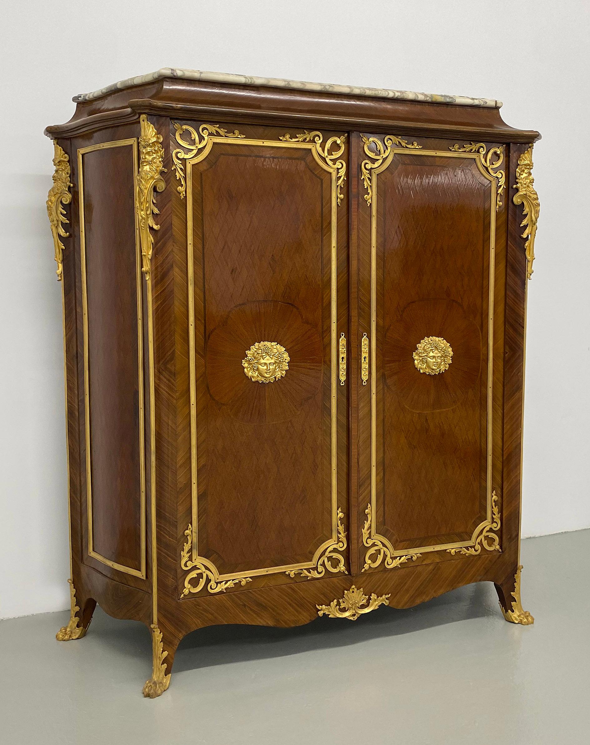A Nice Late 19th Century Gilt Bronze Mounted Transitional Style Parquetry Cabinet

Marble top above two doors. each door centered by a Bacchus mask within sunburst veneer, the corners with bearded men, the cabinet is designed with diamond parquetry