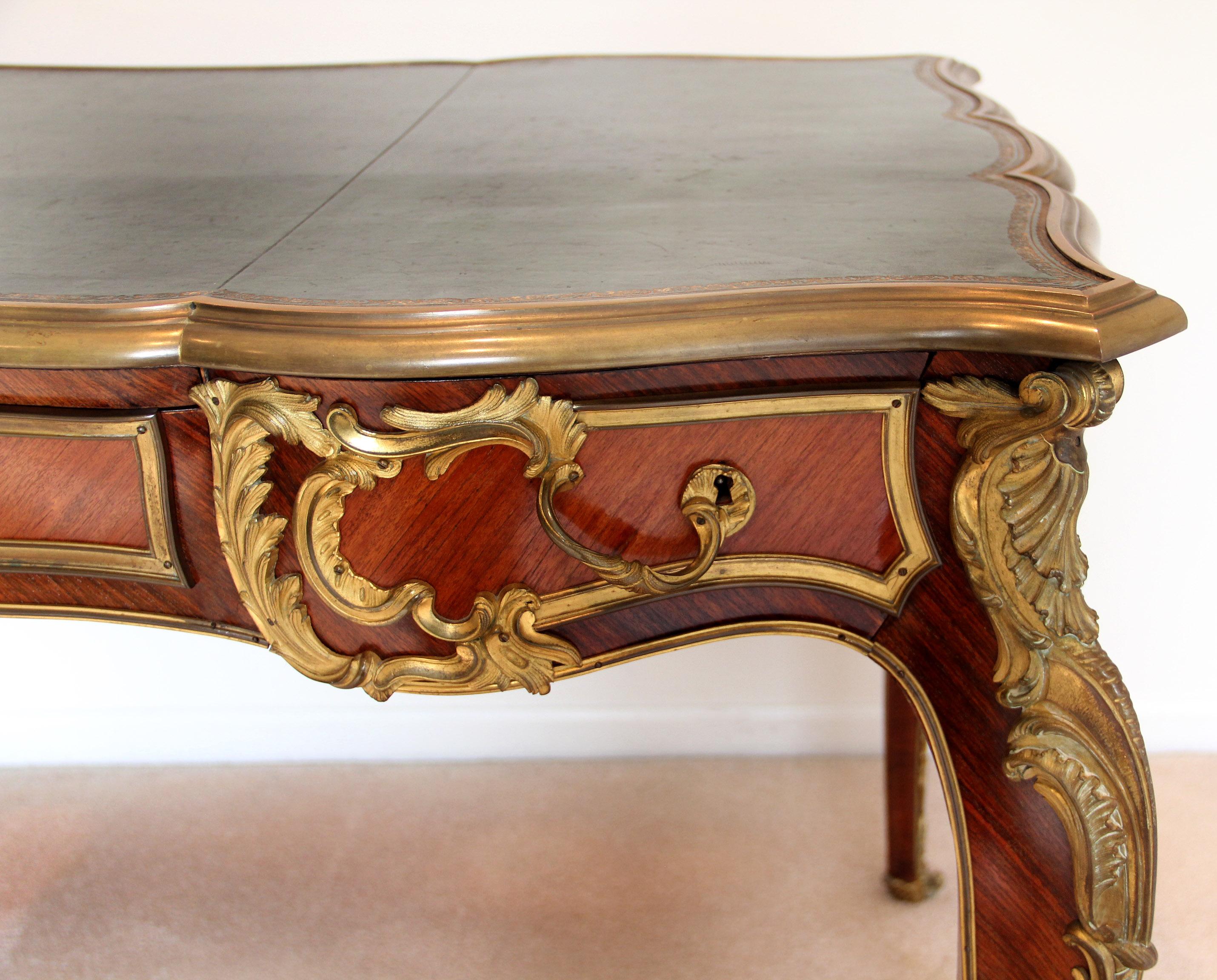 A nice late 19th century Louis XV style gilt bronze mounted bureau plat

The rectangular top with gilt-tooled leather writing-surface within a molded border, above a quarter-veneered serpentine frieze, three drawers to the front and three