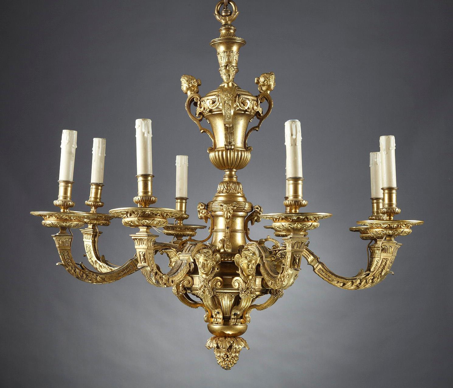 Beautiful chiseled and gilded bronze chandelier with eight square section light-arms, attached to the shaft by female heads and adorned with acanthus leaves and ending with delicately crafted binet and bobeches. The shaft is composed of a vase