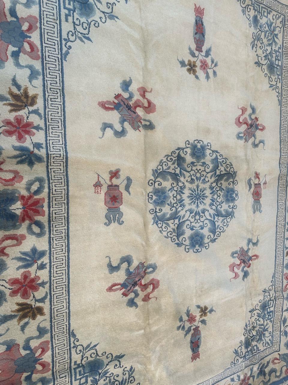 Very beautiful mid century Chinese rug with beautiful Chinese art deco design in a white background with a beautiful floral blue medallion and some Chinese objects around it in pink and blue, and a very beautiful border on a white background adorned