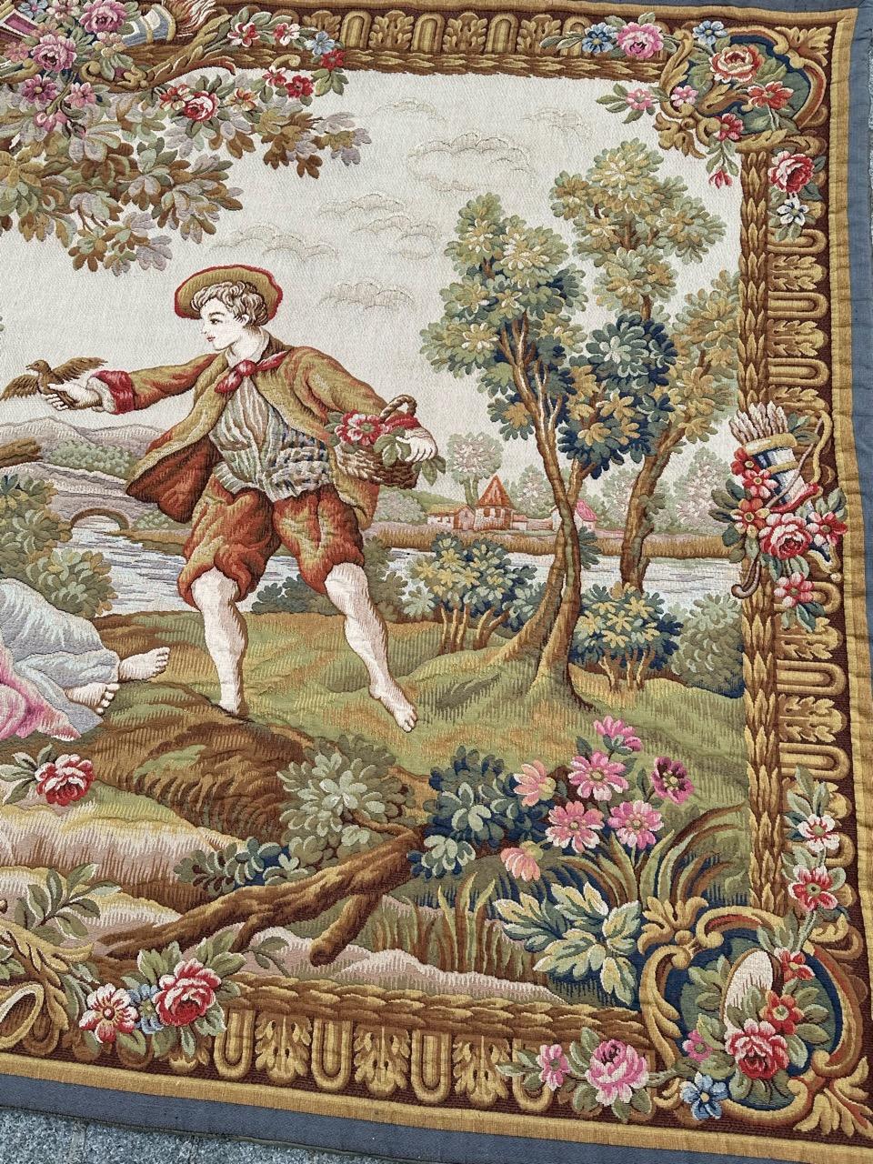 Exceptional mid-20th-century French tapestry woven on Jacquard looms in Halluin stitch with wool and cotton. Inspired by François Boucher, it depicts a gentleman presenting a bird to two ladies in a scenic setting with flowers, trees, and a river.