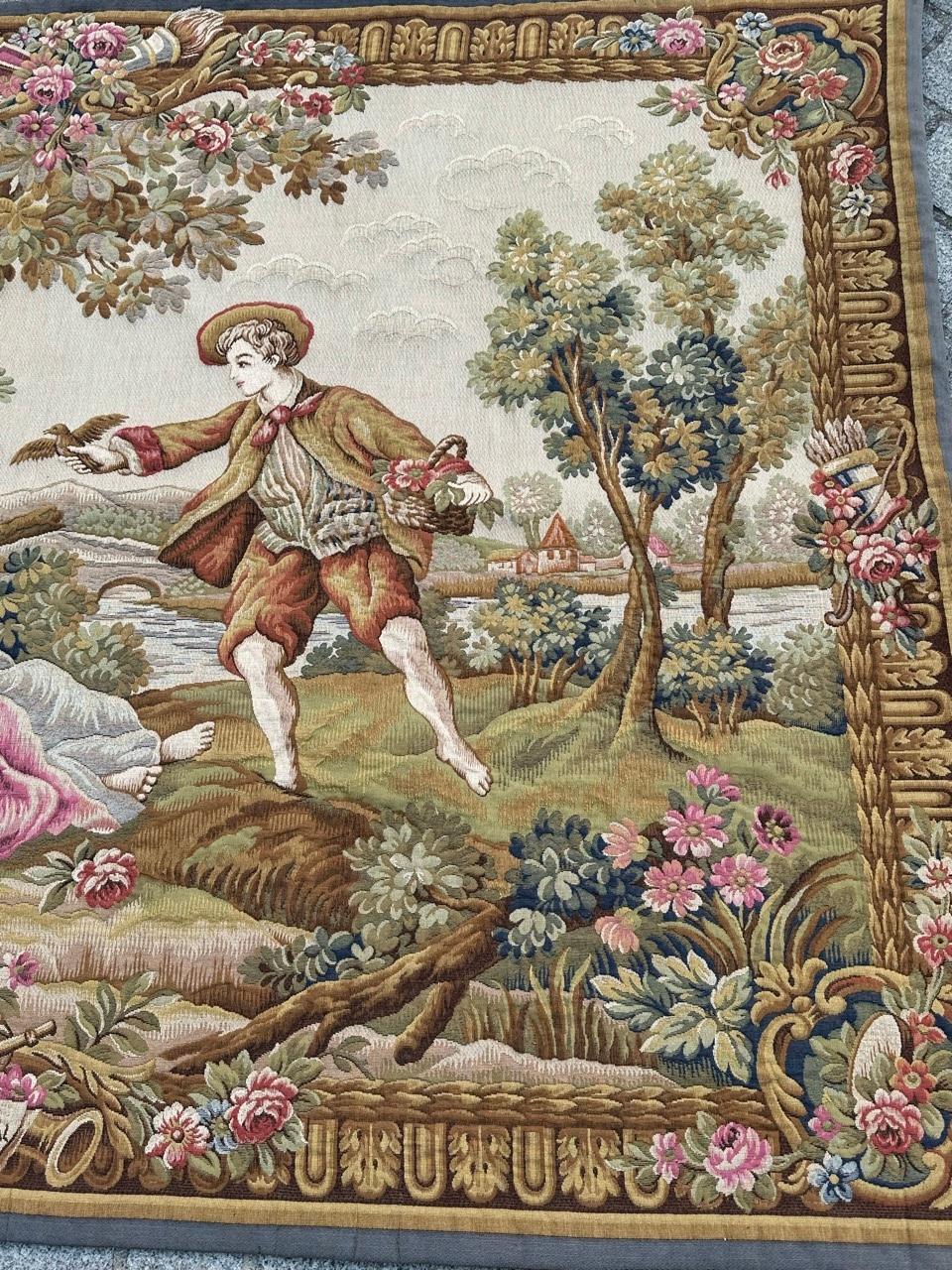 Exceptional mid-20th-century French tapestry woven on Jacquard looms in Halluin stitch with wool and cotton. Inspired by François Boucher, it depicts a gentleman presenting a bird to two ladies in a scenic setting with flowers, trees, and a river.